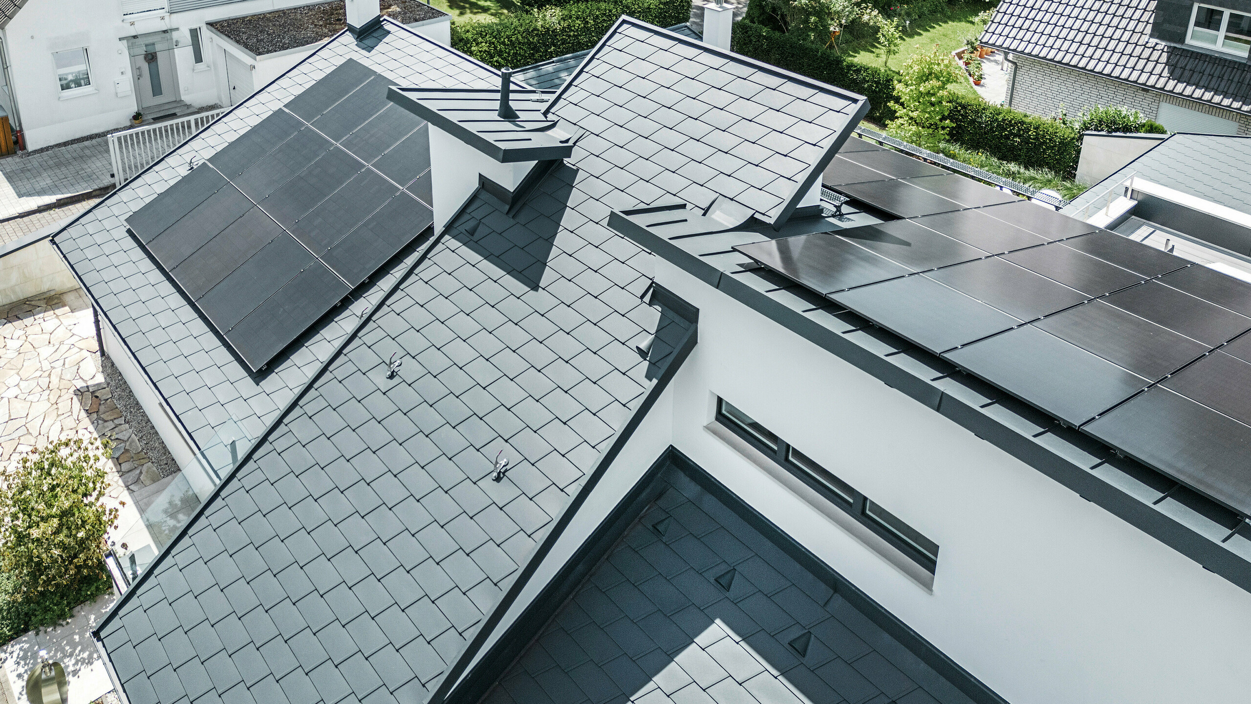 Bird's eye view of the different levels on the roof of a modern detached house in Dortmund were fitted with PREFA DS.19 and PREFALZ roof shingles in the colour P.10 anthracite as well as a large-scale PV system.