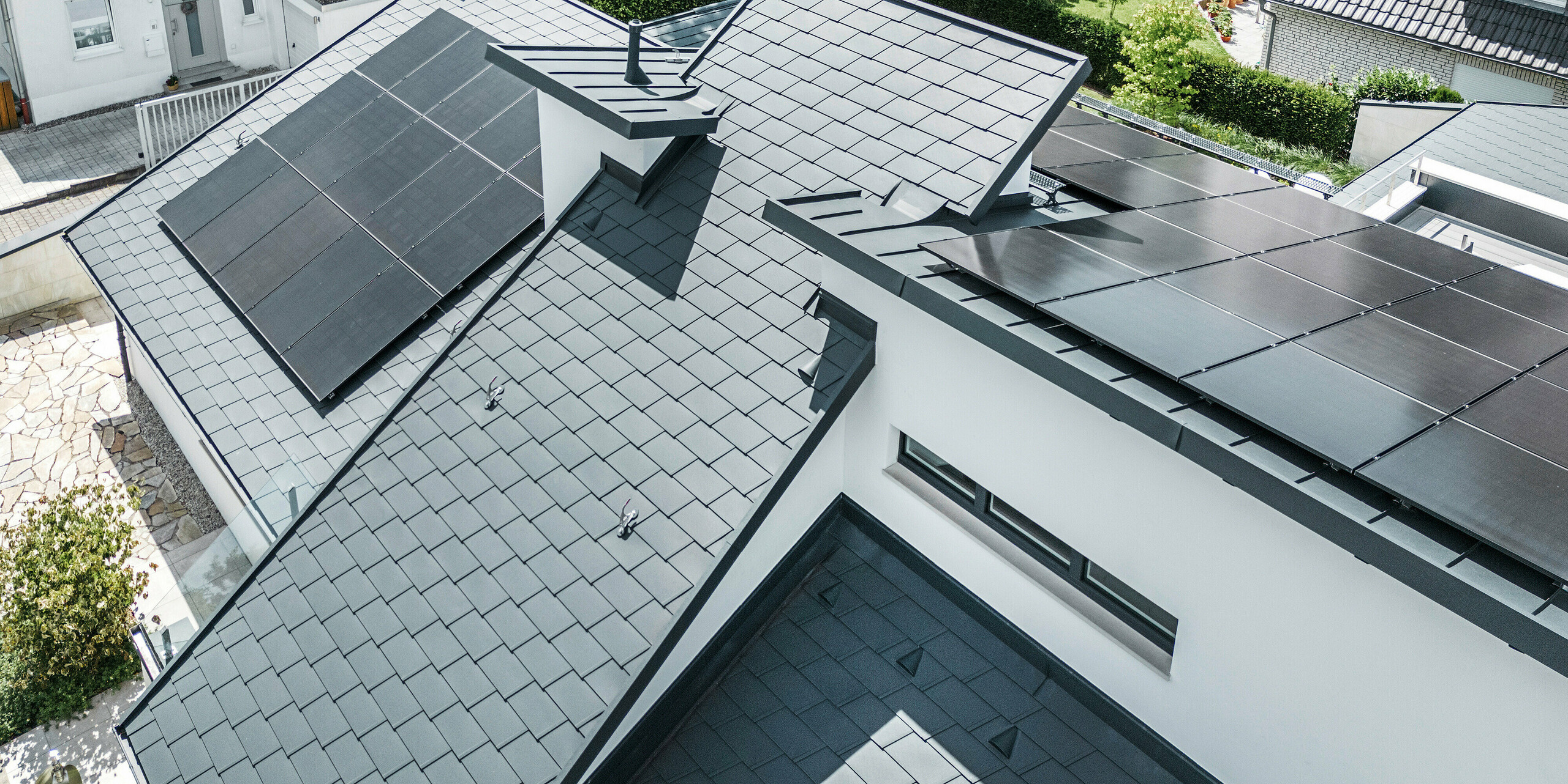 Bird's eye view of the different levels on the roof of a modern detached house in Dortmund were fitted with PREFA DS.19 and PREFALZ roof shingles in the colour P.10 anthracite as well as a large-scale PV system.