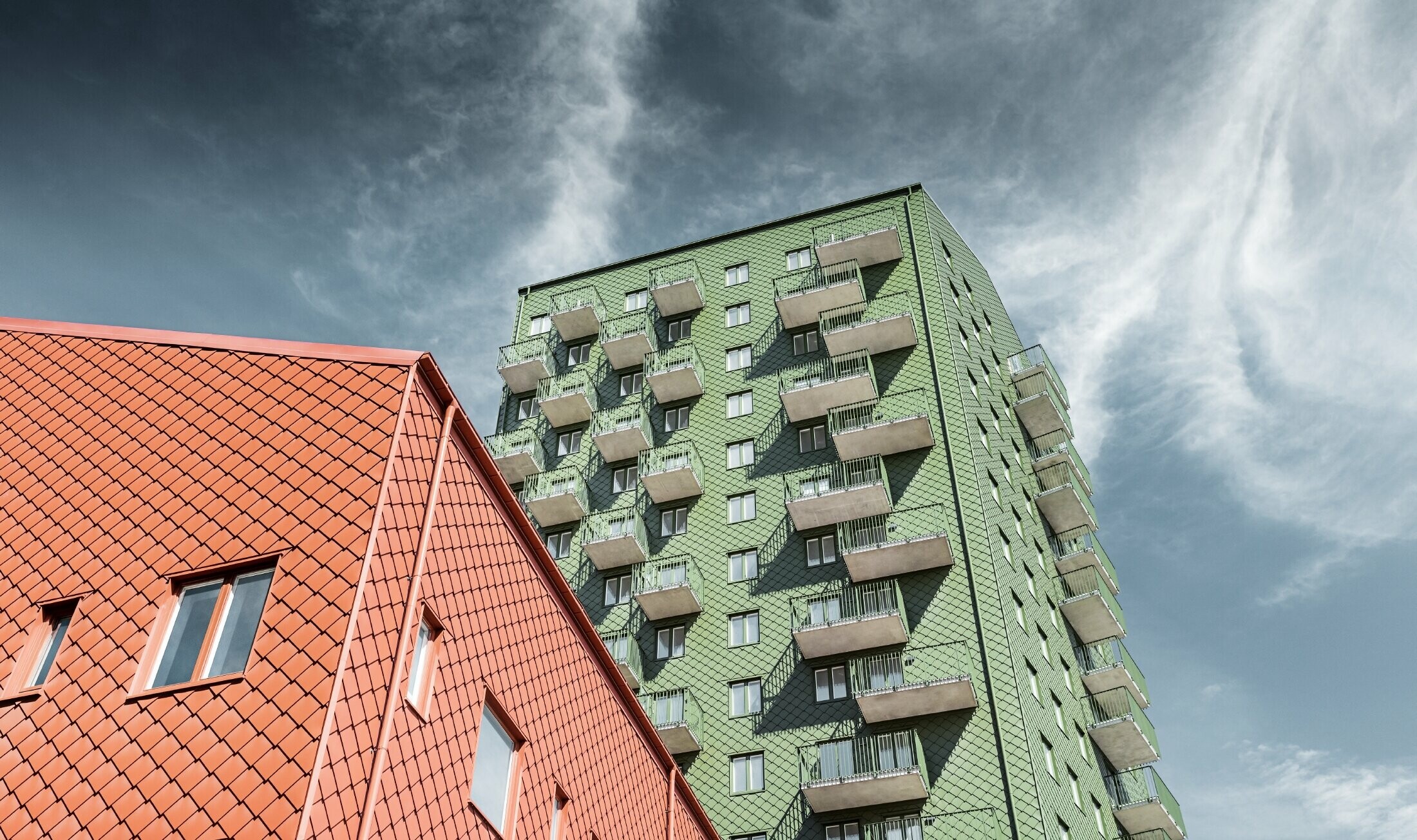 High-rise buildings with balconies with a façade design composed of PREFA rhomboid façade tiles 29 × 29 in olive green and brick red