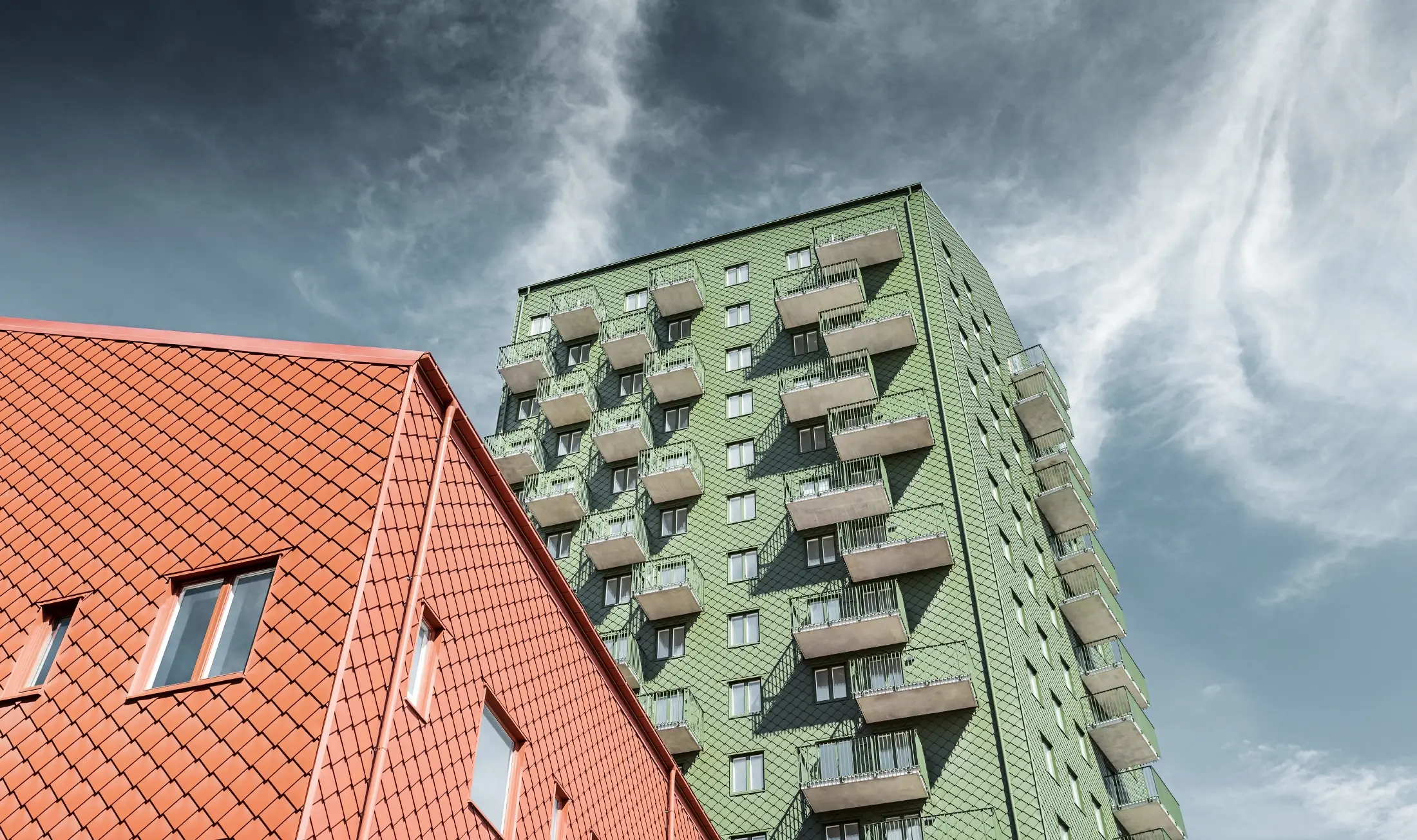 High-rise buildings with balconies with a façade design composed of PREFA rhomboid façade tiles 29 × 29 in olive green and brick red