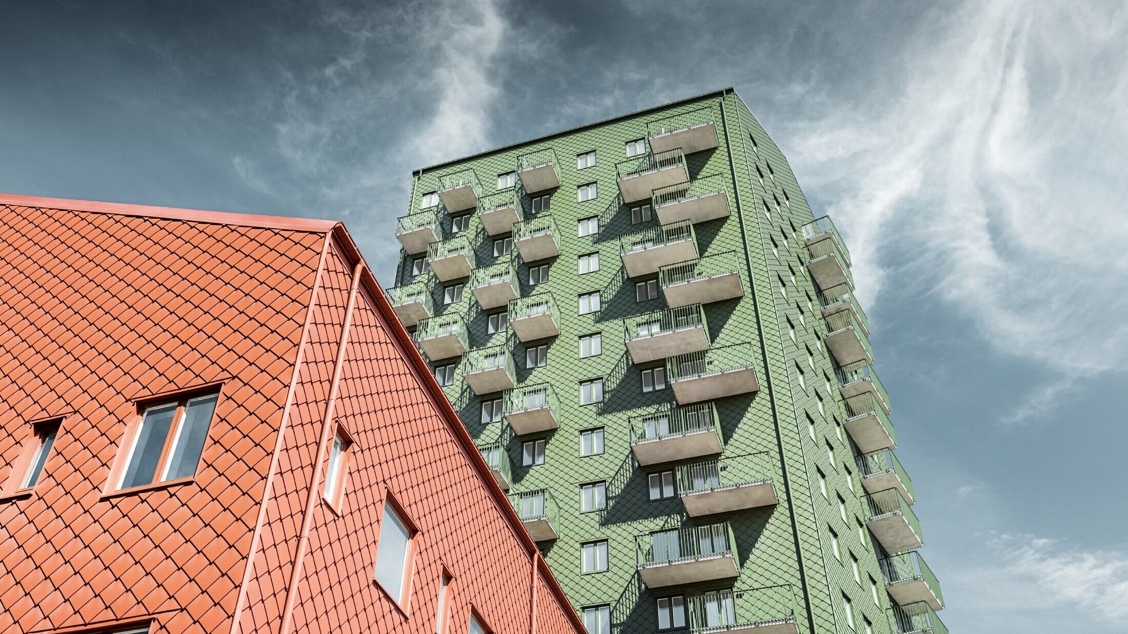 High-rise buildings with balconies with a façade design composed of PREFA rhomboid façade tiles 29 × 29 in olive green and brick red