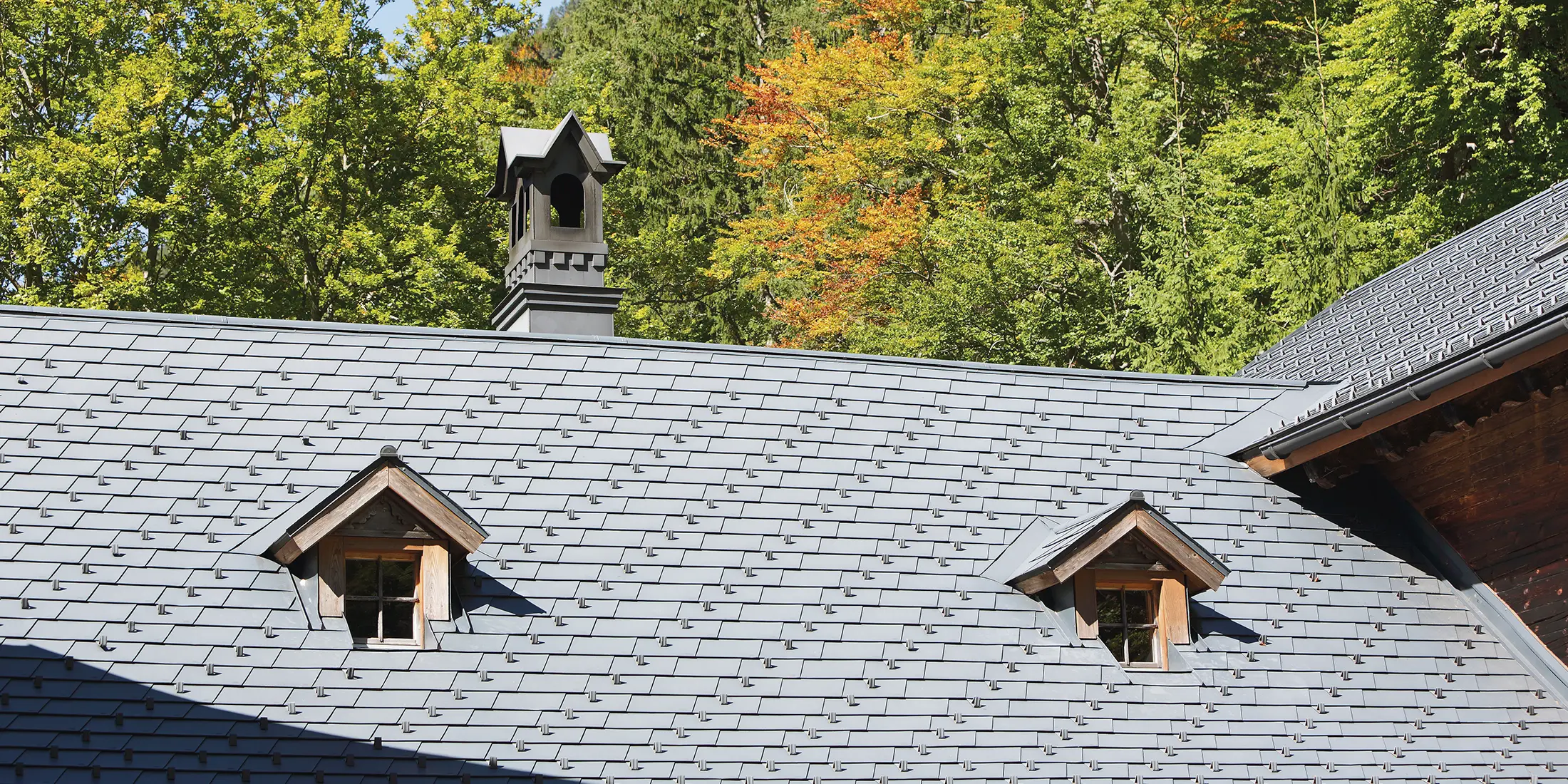 Detailaufnahme des Daches des Rothschildhauses in Langau bei Gaming mit PREFA Dachschindeln in Anthrazit, begleitet von traditionellen Architekturmerkmalen und Natur.