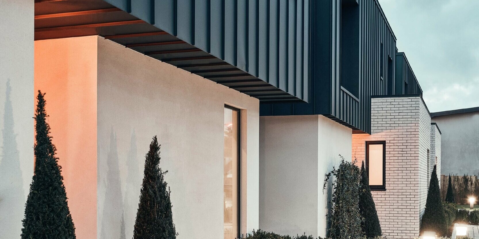 Modern entrance area with some plants, the façade of the upper floor is clad with Prefalz P.10 anthracite.