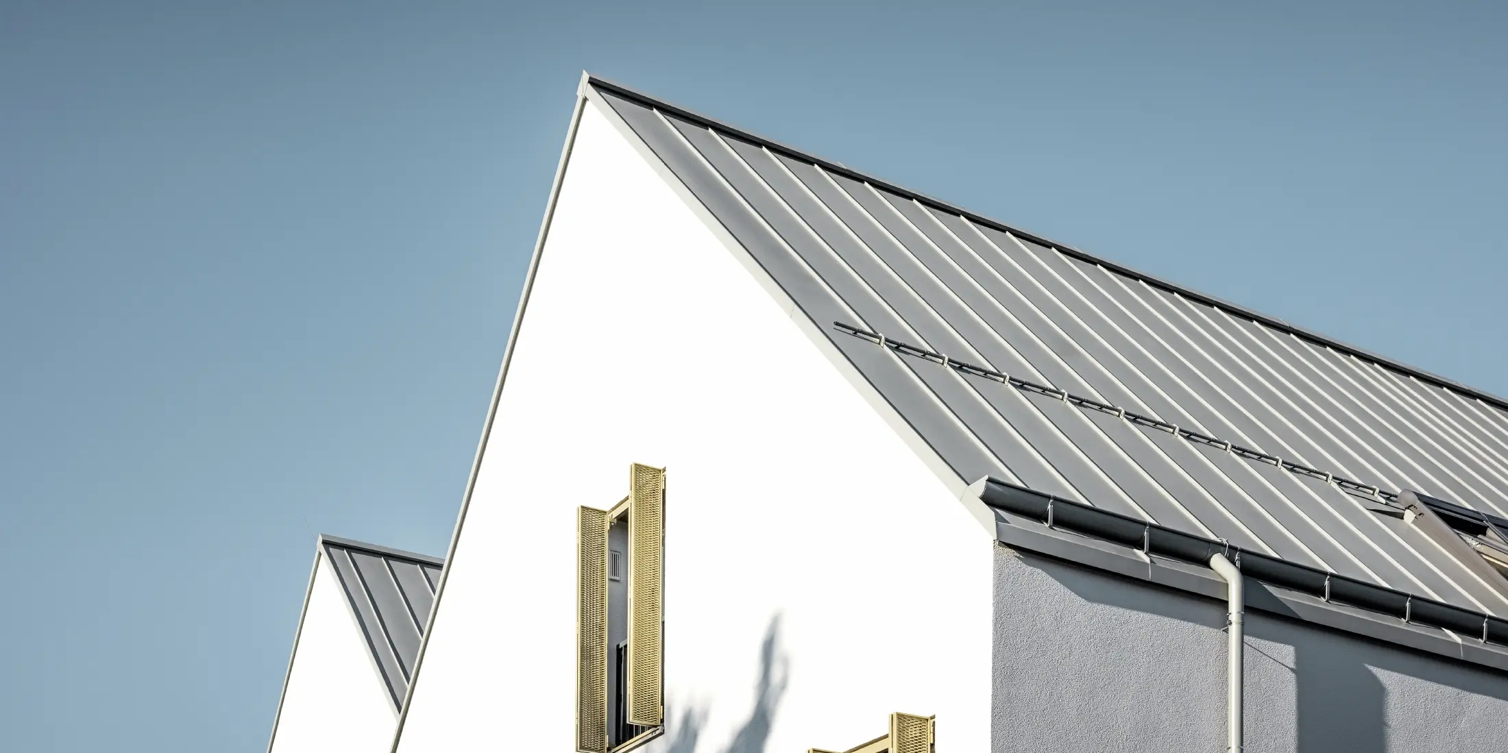 Gable roof without eaves, covered with PREFALZ standing seam in P.10 zinc grey with PREFA on-roof gutter