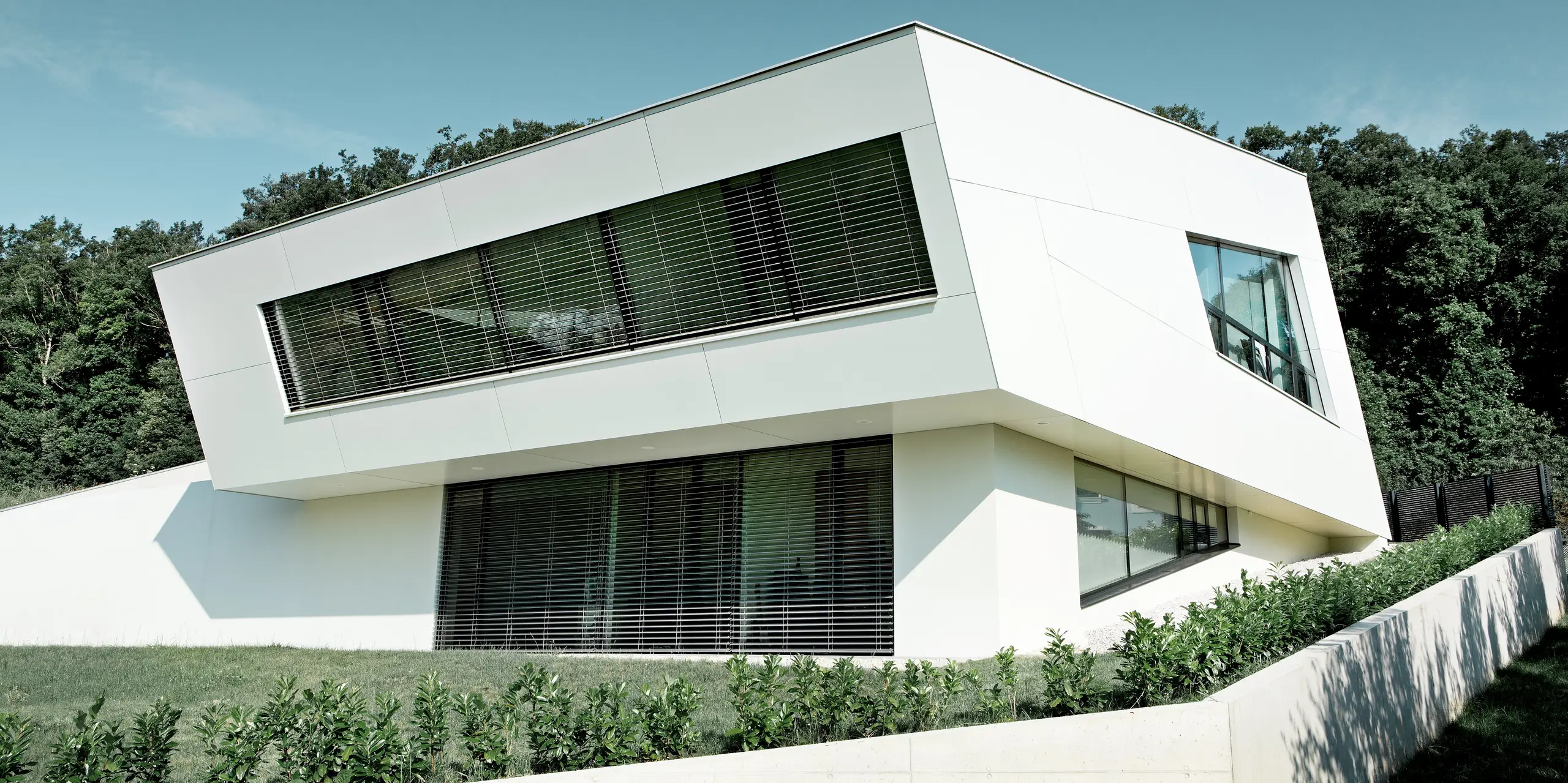 Very modern detached house with a white PREFA composite panel façade and large windows