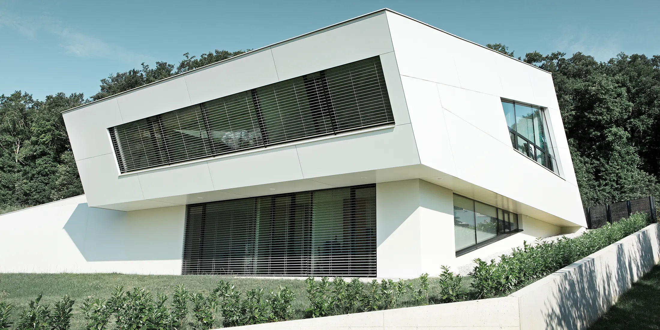 Very modern detached house with a white PREFA composite panel façade and large windows