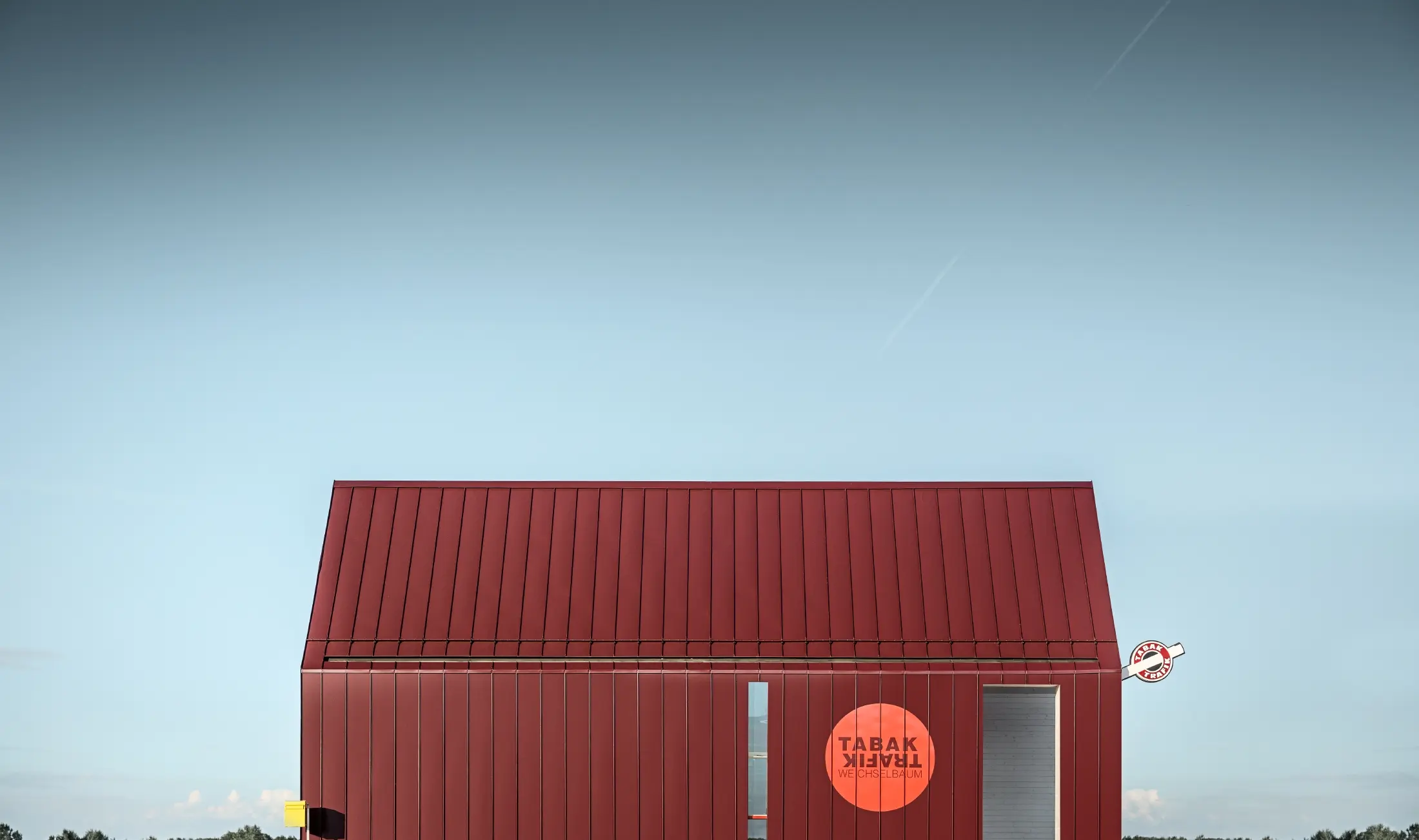 Modern tobacconist with gable roof (without overhanging eaves) and an aluminium coating by PREFA with standing and single lock standing seam in the special colour of black red