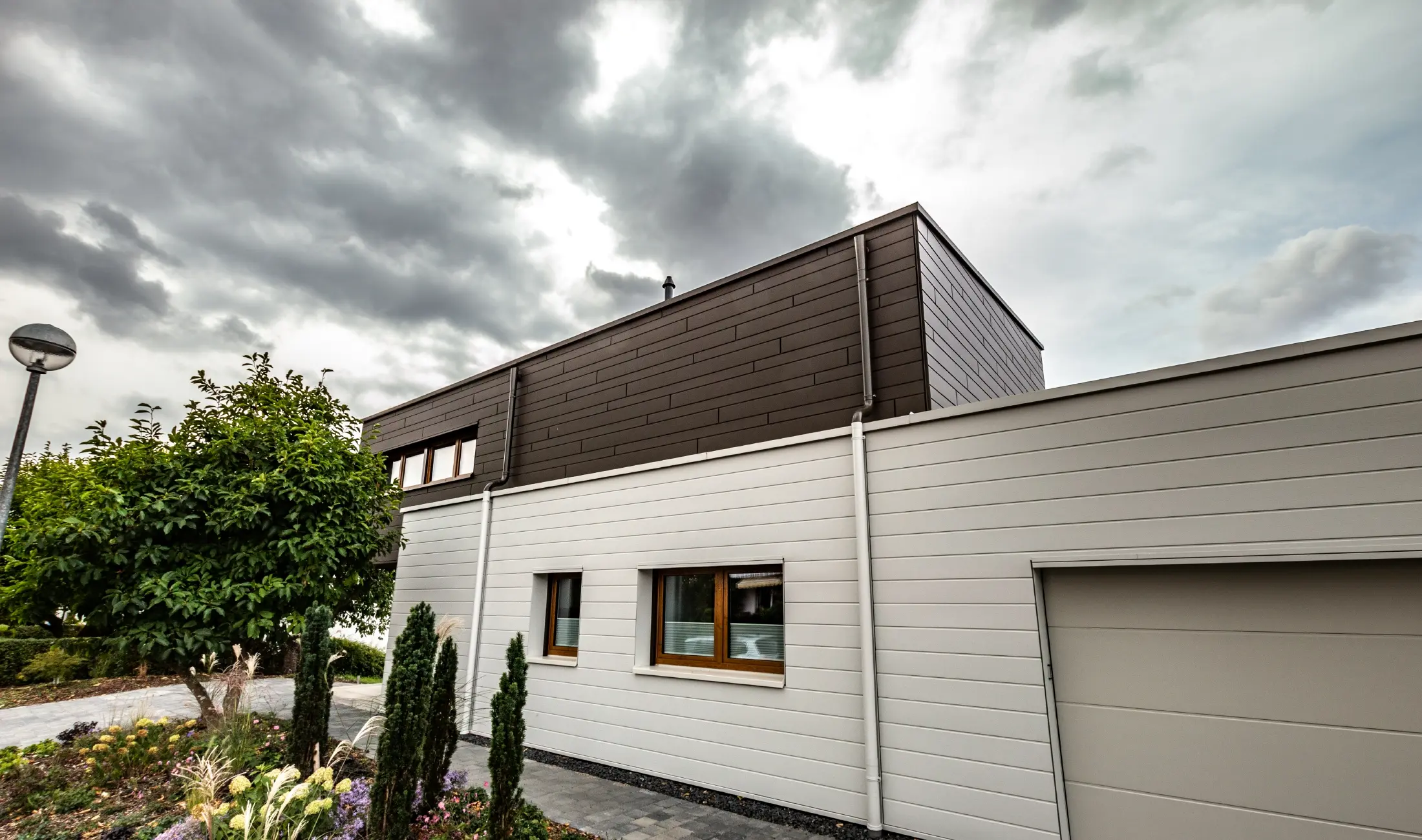 Façade cladding for a garage with horizontal PREFA sidings in white with parapet outlet connector.