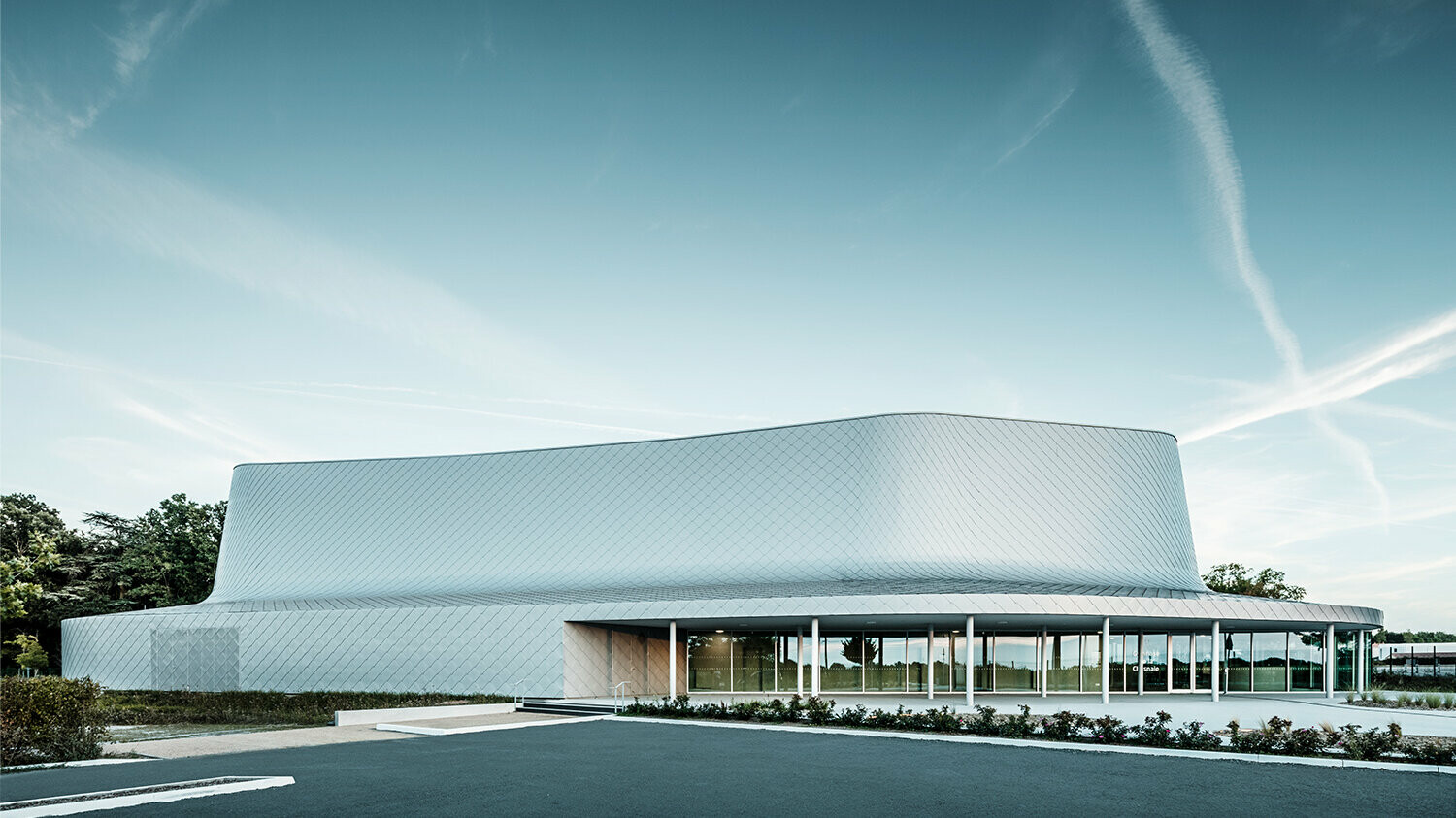 Side view of the building with the courtyard. The glazing in the entrance area creates the impression that the building is partially transparent.