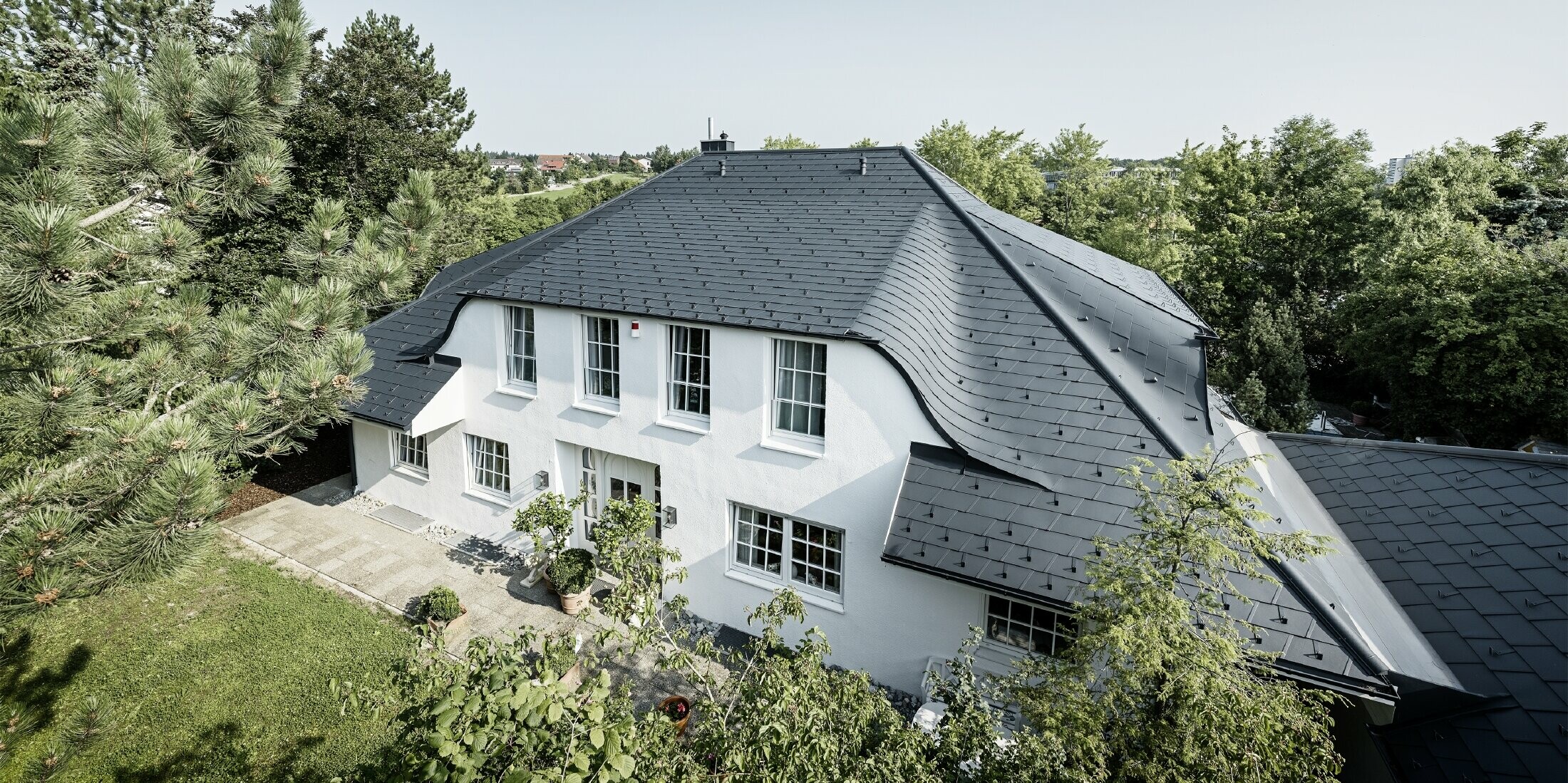Hipped roof with many curved dormers, covered with DS.19 aluminium roof shingles in anthracite