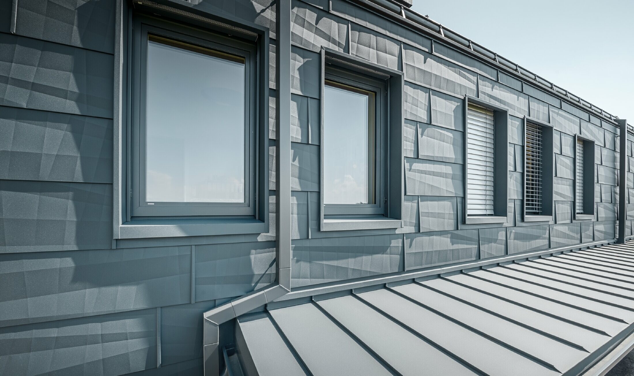 Modern apartment building with a large glazed front, and roof and façade clad with PREFA FX.12 roof and façade panels in anthracite