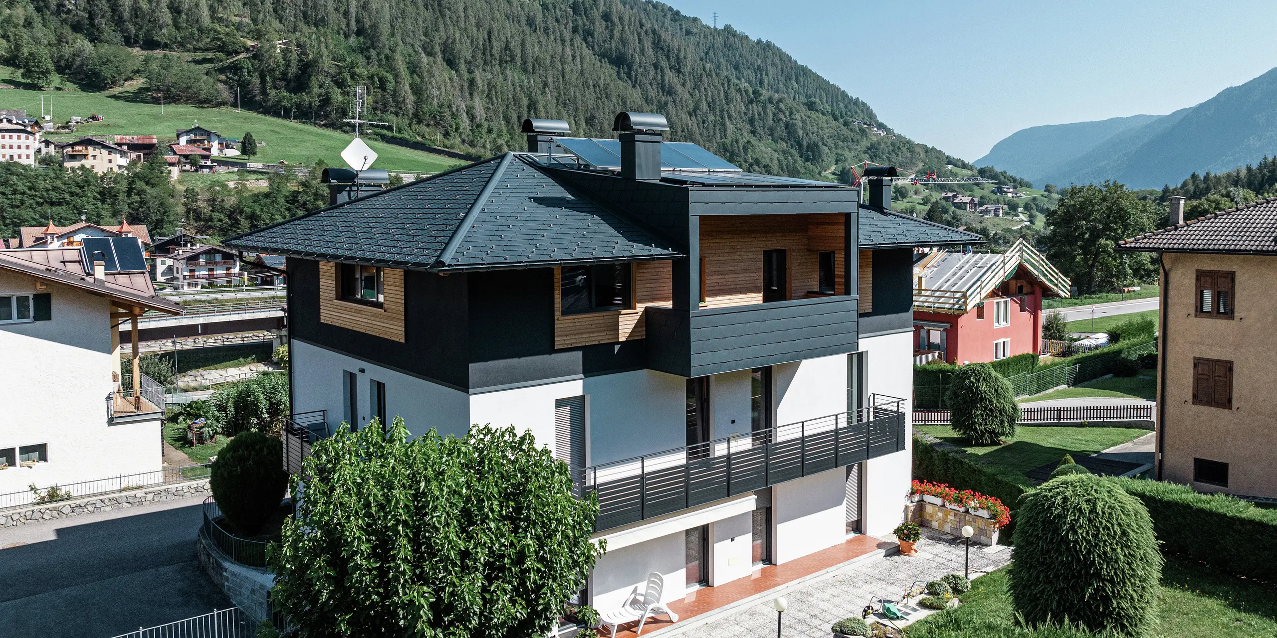 Vogelperspektive auf das Wohnhaus in Commezzadura mit PREFA Dachschindeln DS.19 in P.10 Anthrazit. Teile der Fassade des Dachgeschosses wurden mit Holz verkleidet, wodurch ein harmonischer Gesamteindruck entsteht. Auch die überdachten Balkone sind mit dem hochwertigen Aluminiumprodukt eingedeckt.