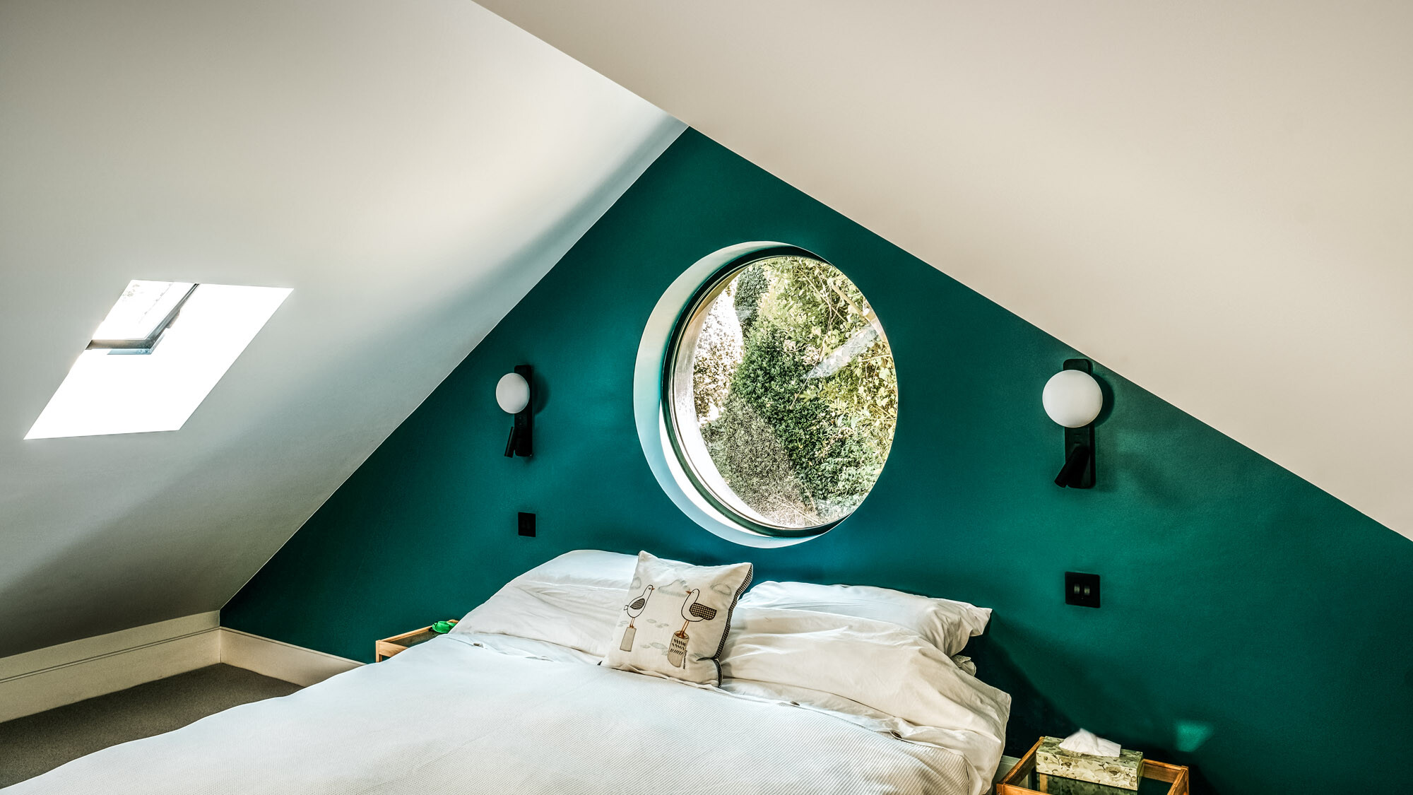 Interior view of one of the stylishly furnished bedrooms in the attic with a round window.