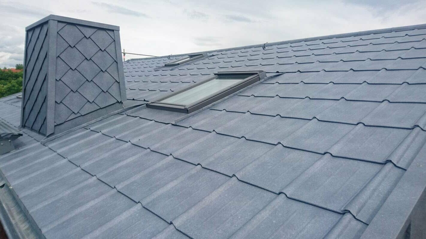 Close-up of a roof renovated with PREFA roof tiles in P.10 stone grey including chimney cladding