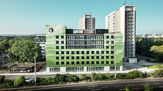 Side view of the residential and commercial building ‘Pick-Nick’ at Straßburger Platz in Dresden with a striking PREFA façade made of robust aluminium. The modern building with its clear lines and large windows integrates well into the urban environment between residential high-rises and green spaces. The concise design sets architectural accents.