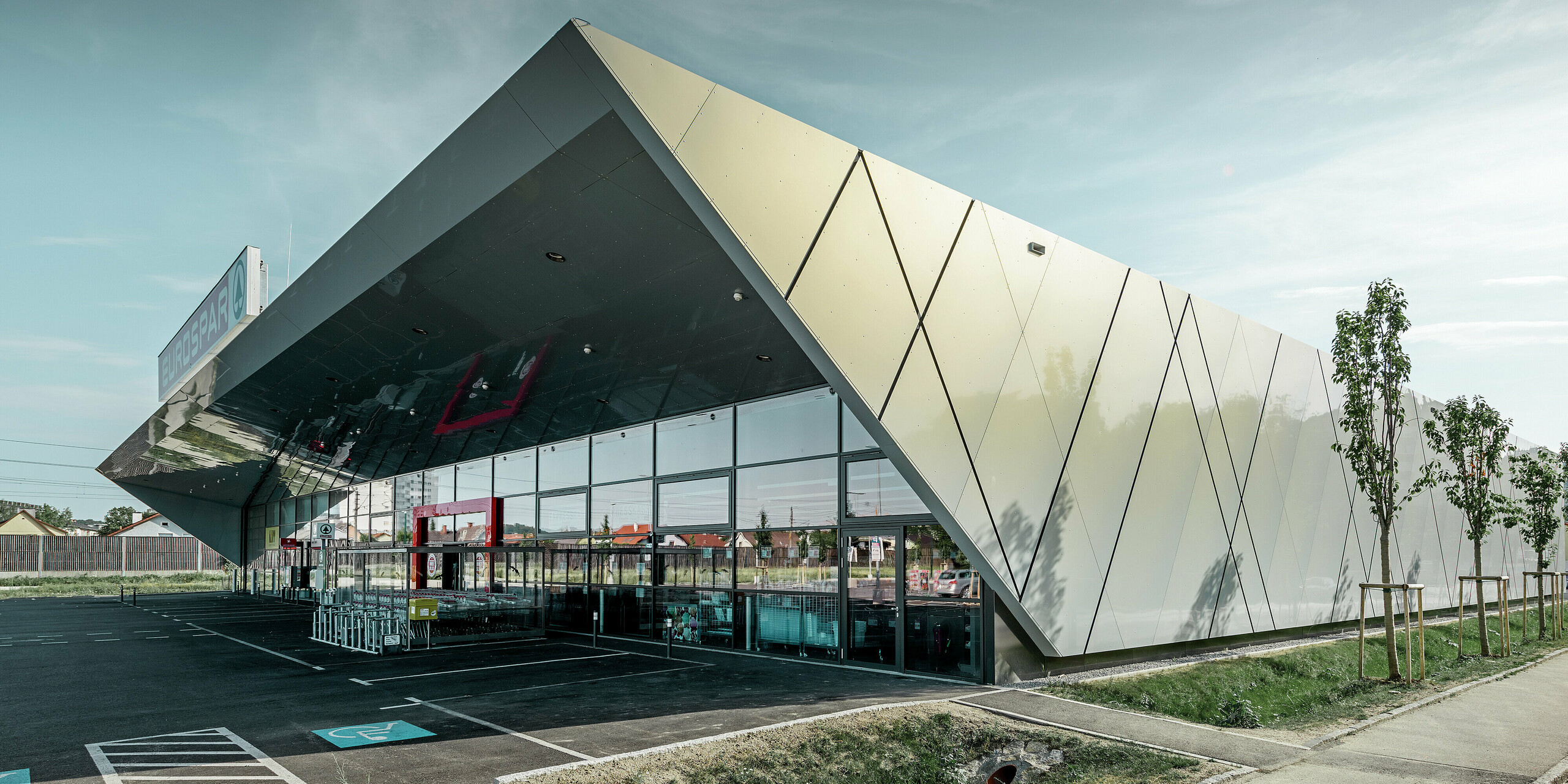 Entrance area of the new Eurospar store in Wels with a modern PREFA façade tile in silver gold. The composite aluminium tiles shimmer in different colours depending on the angle of the sun.