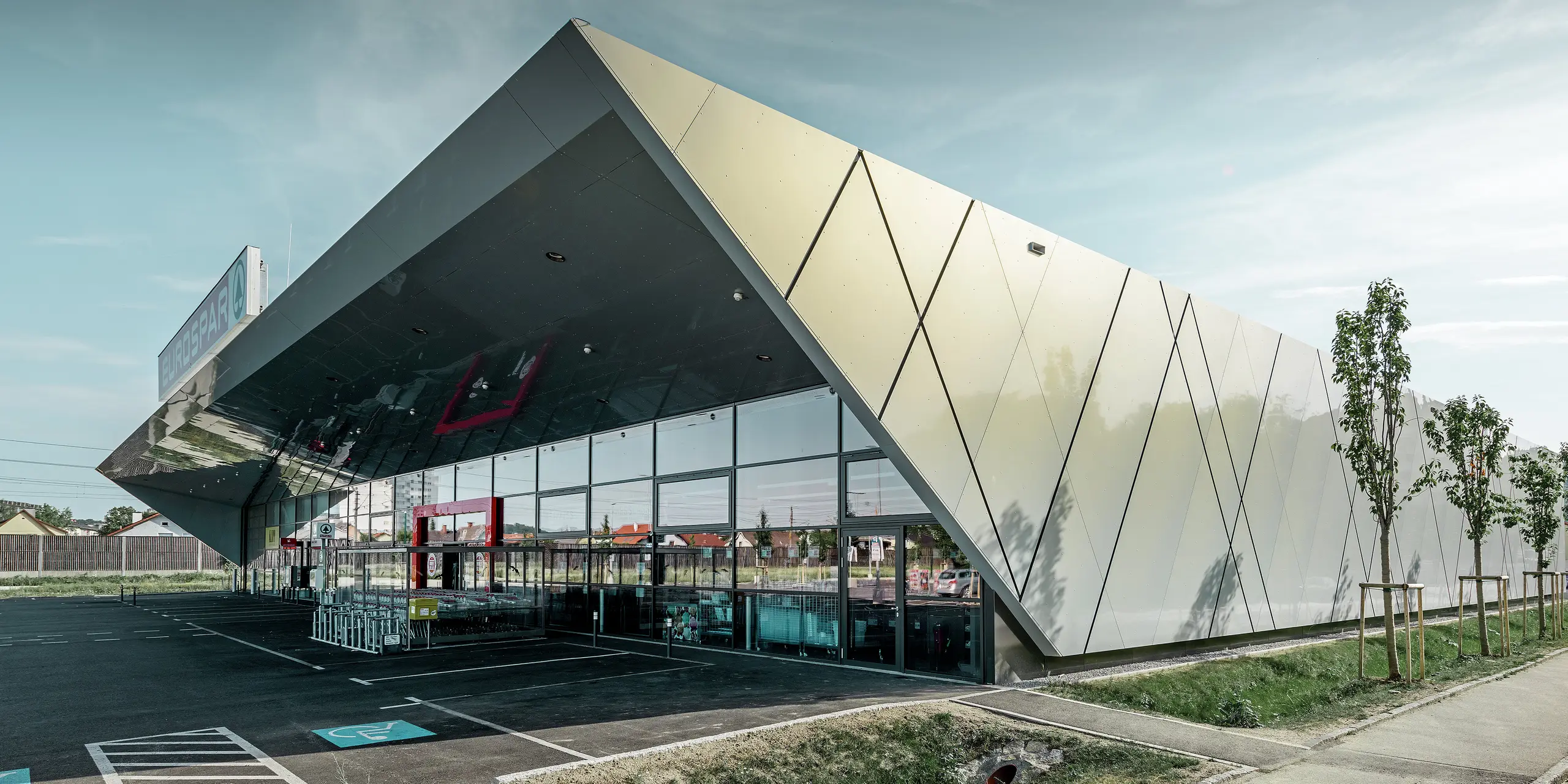 Entrance area of the new Eurospar store in Wels with a modern PREFA façade tile in silver gold. The composite aluminium tiles shimmer in different colours depending on the angle of the sun.