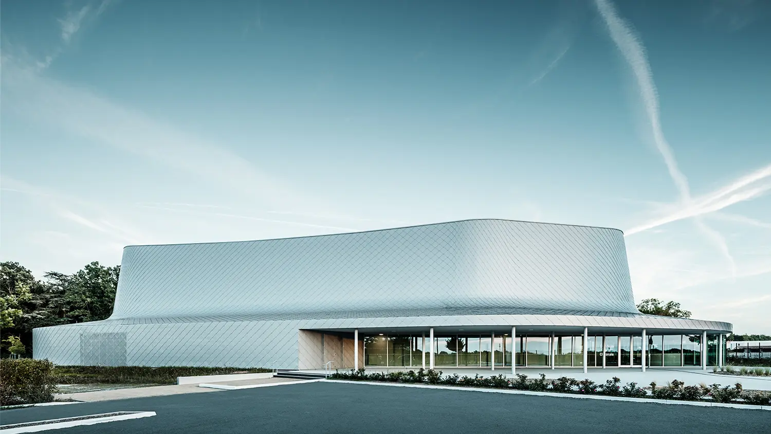 Side view of the building with the courtyard. The glazing in the entrance area creates the impression that the building is partially transparent.