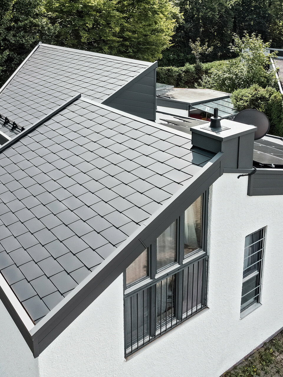 Ein Einfamilienhaus, das mit PREFA Dachschindeln DS.19 in schwarz eingedeckt wurde. Für Teile der Fassade wurden PREFA Sidings in P.10 dunkelgrau verwendet. 