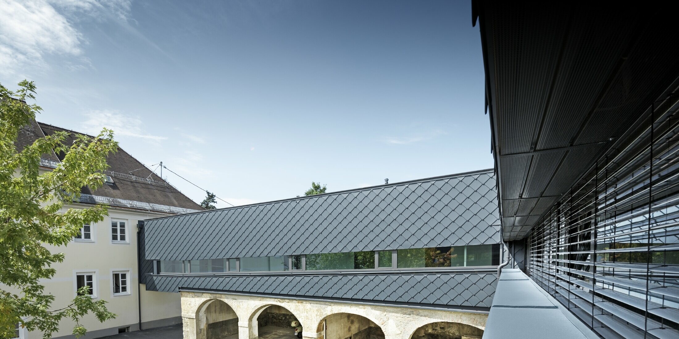 The upper floor of the listed building was clad with PREFA rhomboid façade tile 29 in anthracite, thus the old structures on the ground floor harmonise perfectly with the new rhomboid tiles.