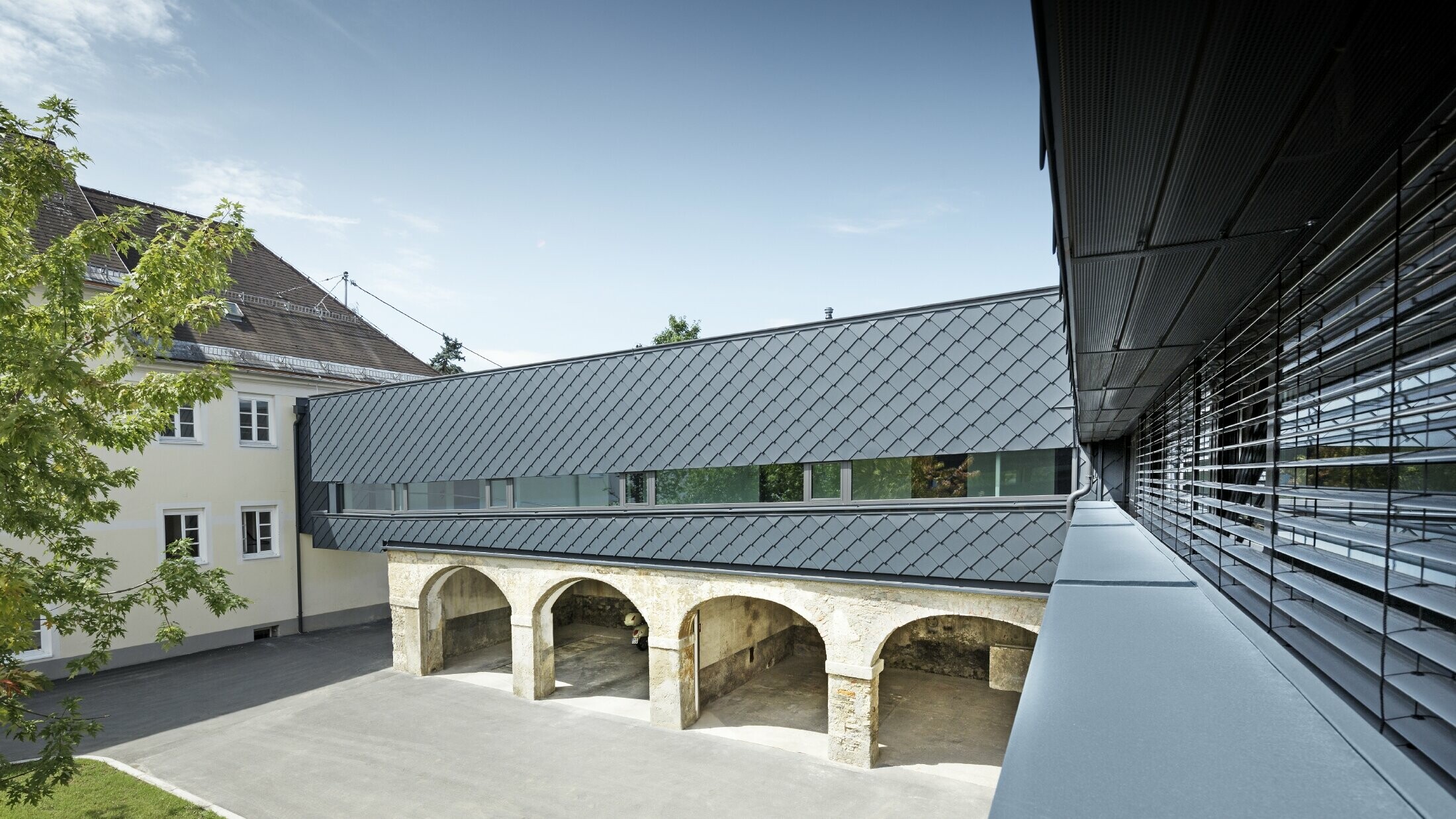 The upper floor of the listed building was clad with PREFA rhomboid façade tile 29 in anthracite, thus the old structures on the ground floor harmonise perfectly with the new rhomboid tiles.