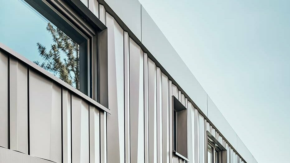 Lateral view of the detached house. The façade is covered with color aluminium coils in bronze. 