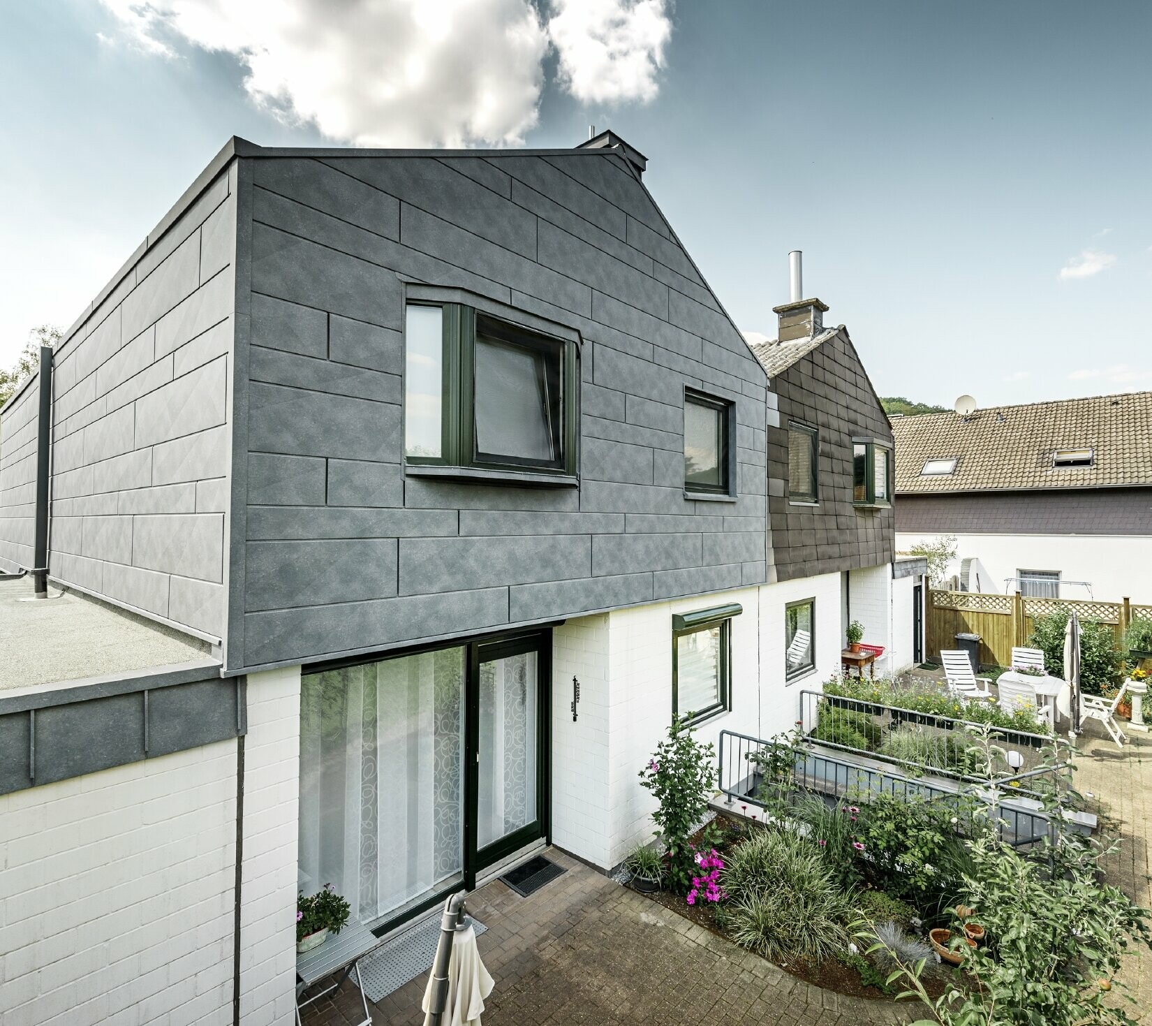 The upper part of the semi-detached house was refurbished with the PREFA Siding.X façade element in P.10 stone grey. Next to it is the semi-detached house before the refurbishment for comparison.