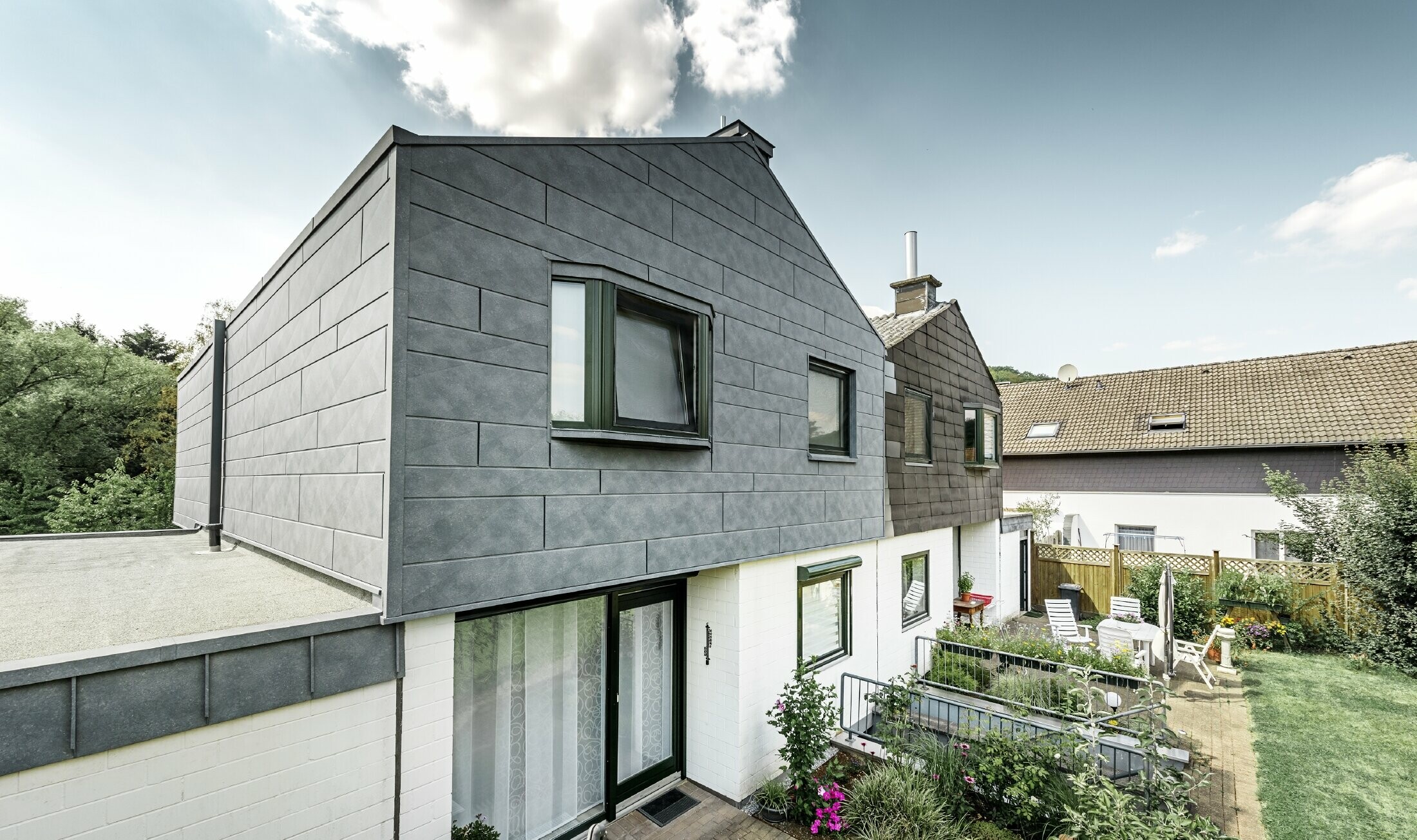 The upper part of the semi-detached house was refurbished with the PREFA Siding.X façade element in P.10 stone grey. Next to it is the semi-detached house before the refurbishment for comparison.