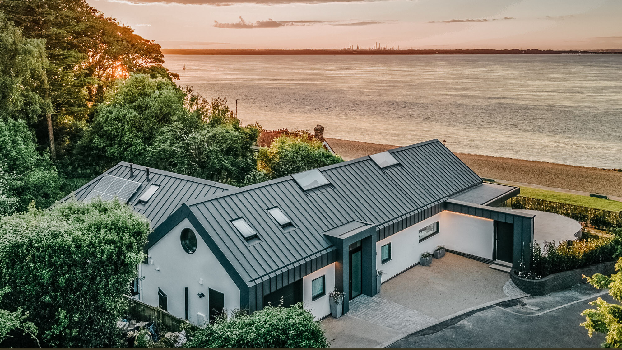 The bungalow from the street side from a lateral bird's eye view, the beach and the sea spreading out before it.