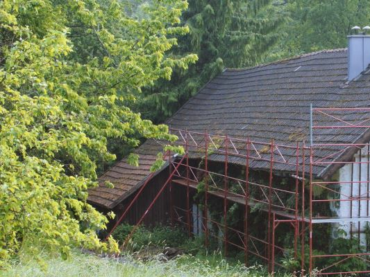 Old roof on a rural cottage (with scaffolding) just before the roof was renovated with PREFA shingles