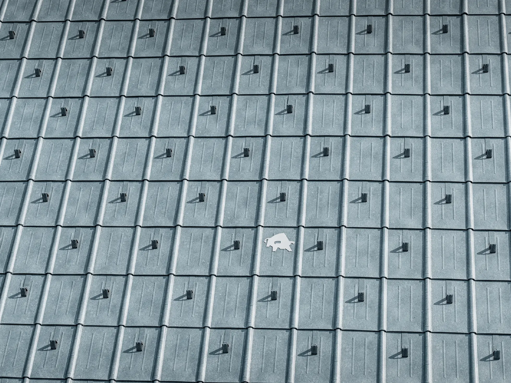 PREFA roof panel laid with PREFA bull logo in P.10 stone grey; roof surface with PREFA sheet metal roof