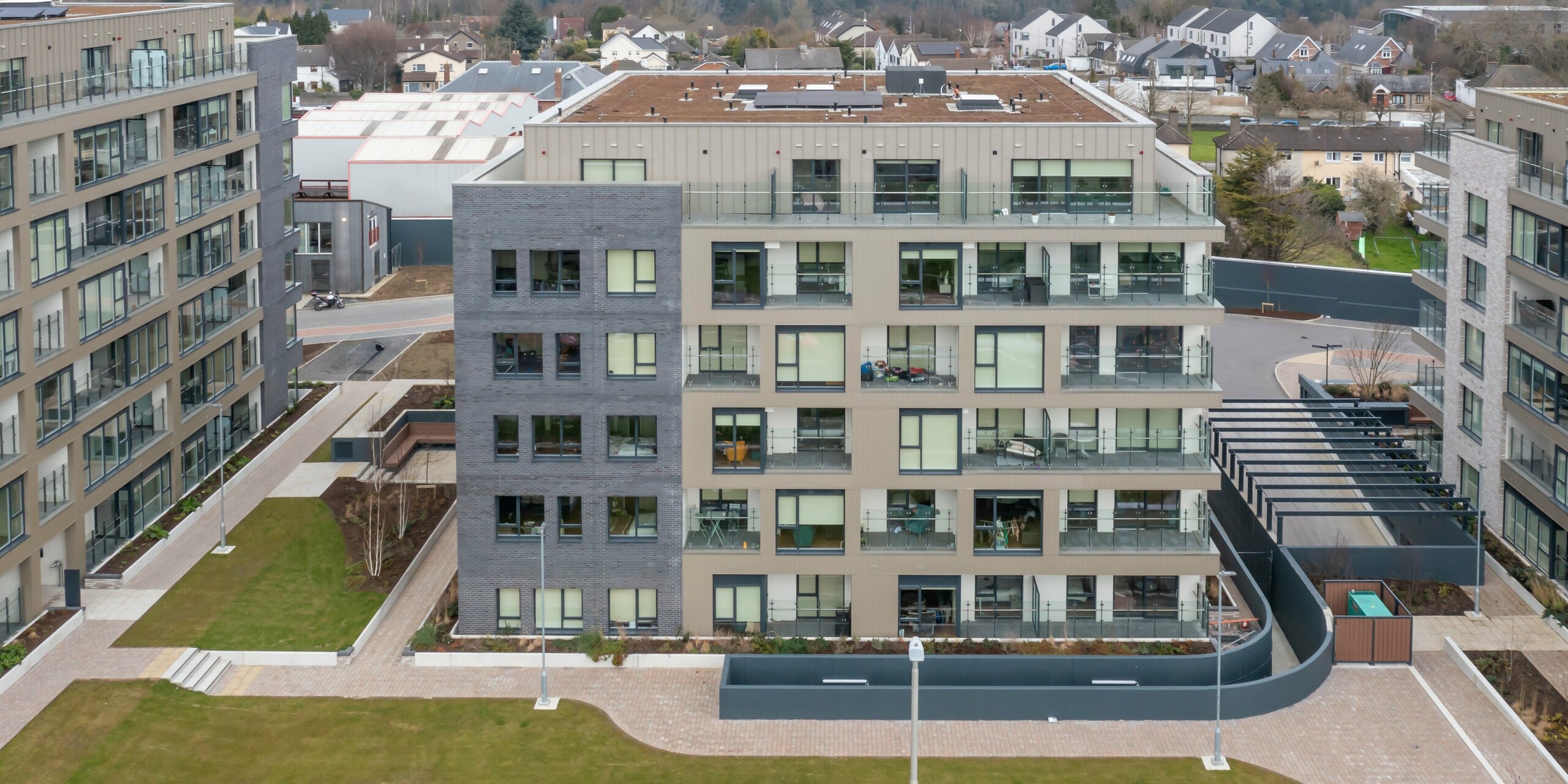 Drone photo of the Palmers Gate residential complex in Palmerstown, Dublin, Ireland. The complex consists of several blocks of flats with bronze-coloured PREFA cladding and the PREFALZ façade system. The façade combines high quality sheet metal cladding with brick elements and large glass windows. The outdoor areas are designed with green spaces, footpaths and planters to create a pleasant environment for the residents. In total, approx. 1,700 m² of PREFA siding and approx. 1,200 m² of PREFALZ façade system were used. The aluminium products are renowned for their durability and aesthetic appearance.