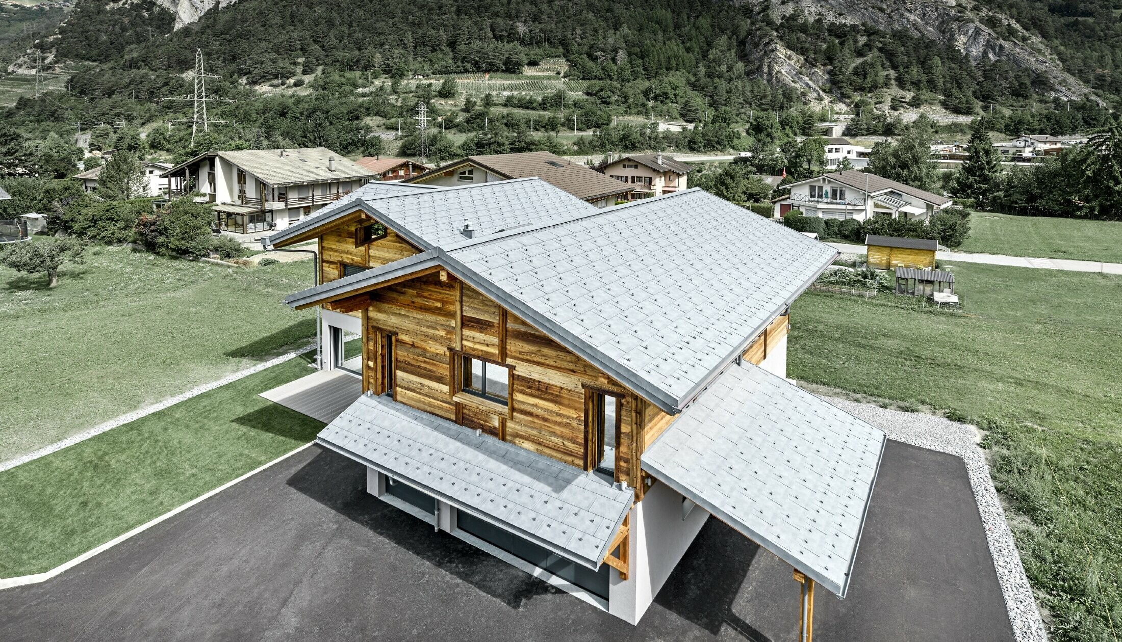 Aerial view of Chalet Fabrice. The cottage was clad in the PREFA R.16 roof tile in stone grey with snow guards. The upper part of the building is clad in a rustic wooden façade.