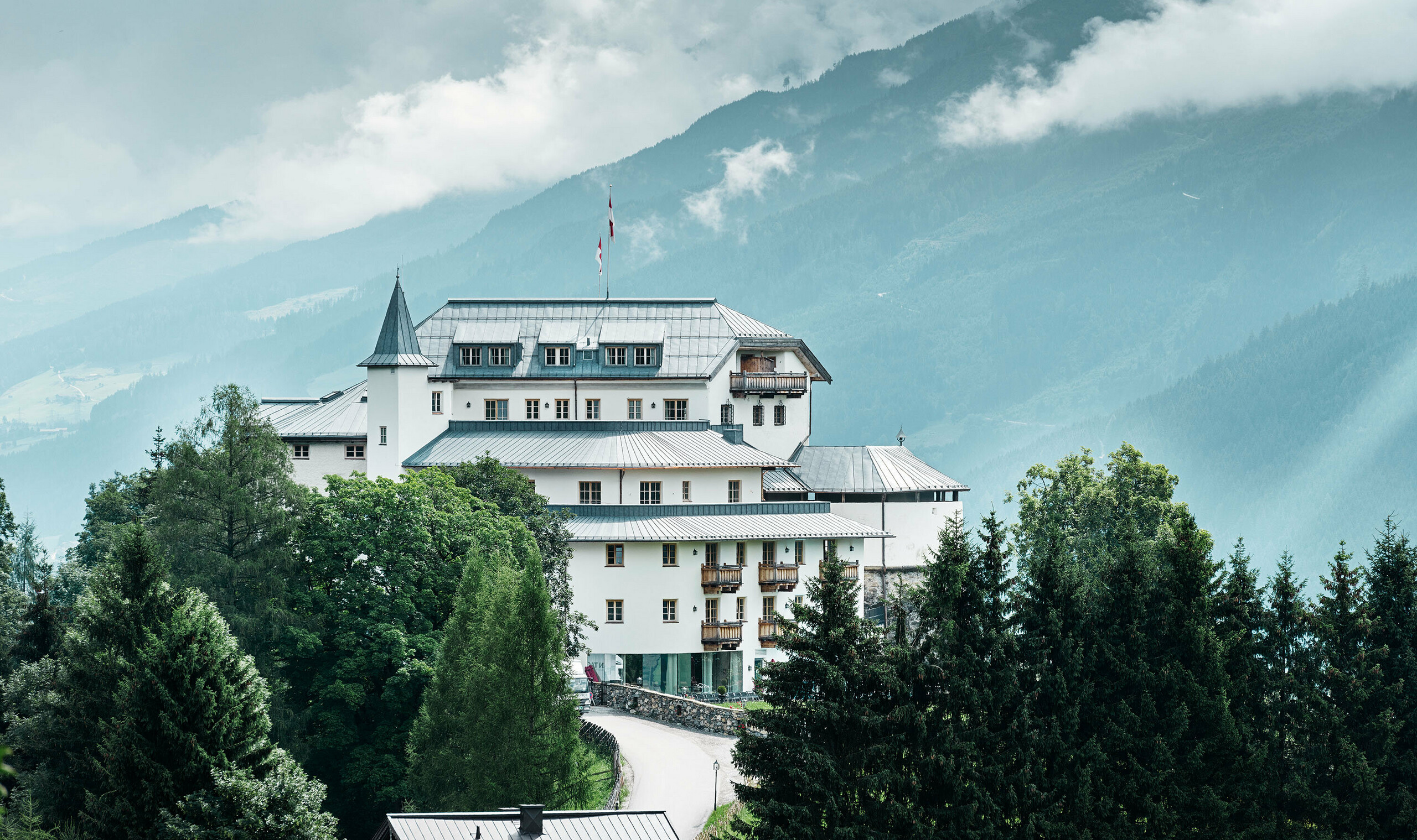 Mittersill Castle surrounded by trees and mountains with a recently renovated Prefalz roof in stone grey