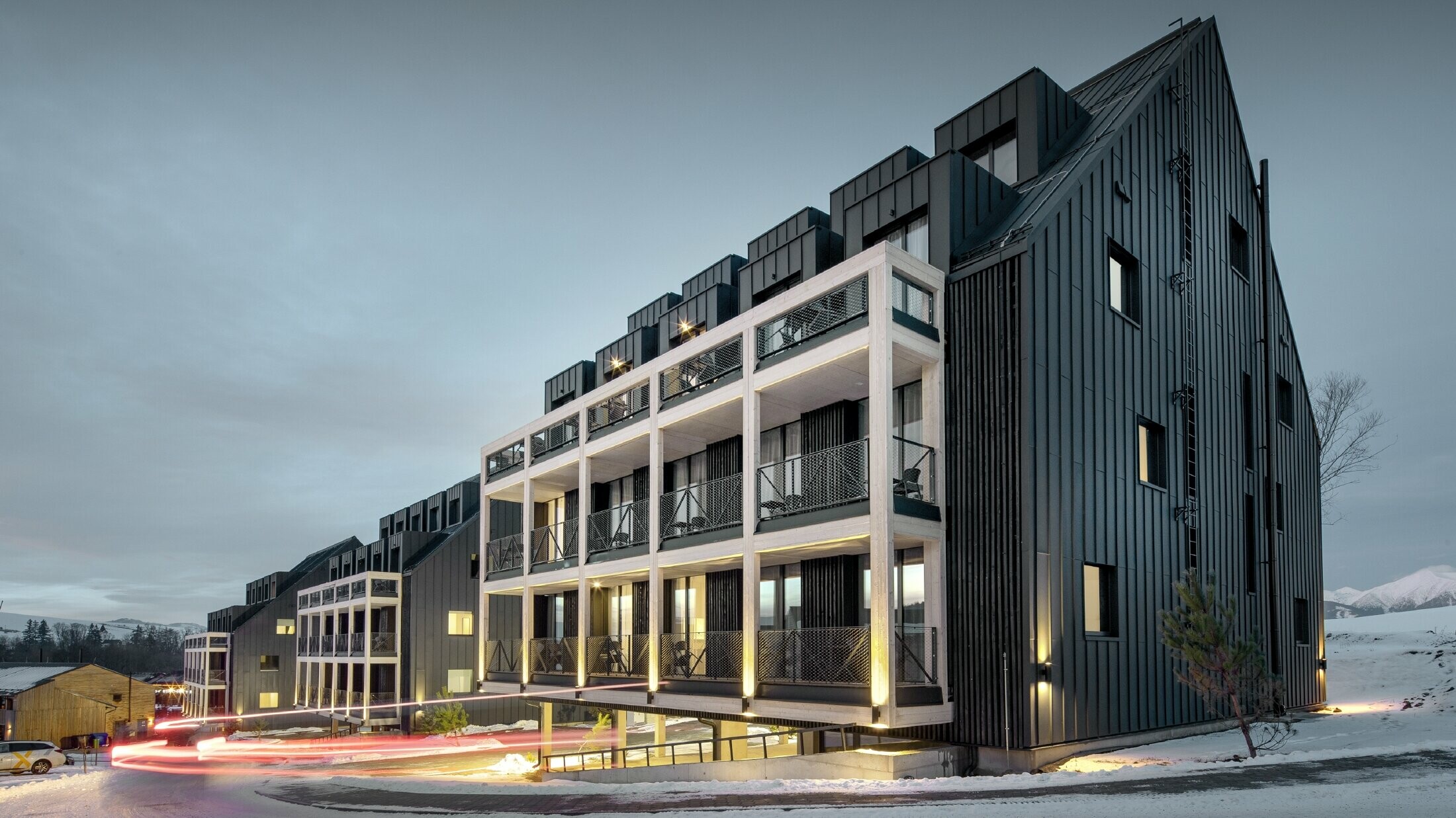 Ski resort in Slovakia with balconies and dormers, the façade is clad with PREFALZ in anthracite, just like the gable roof, snow-covered surroundings