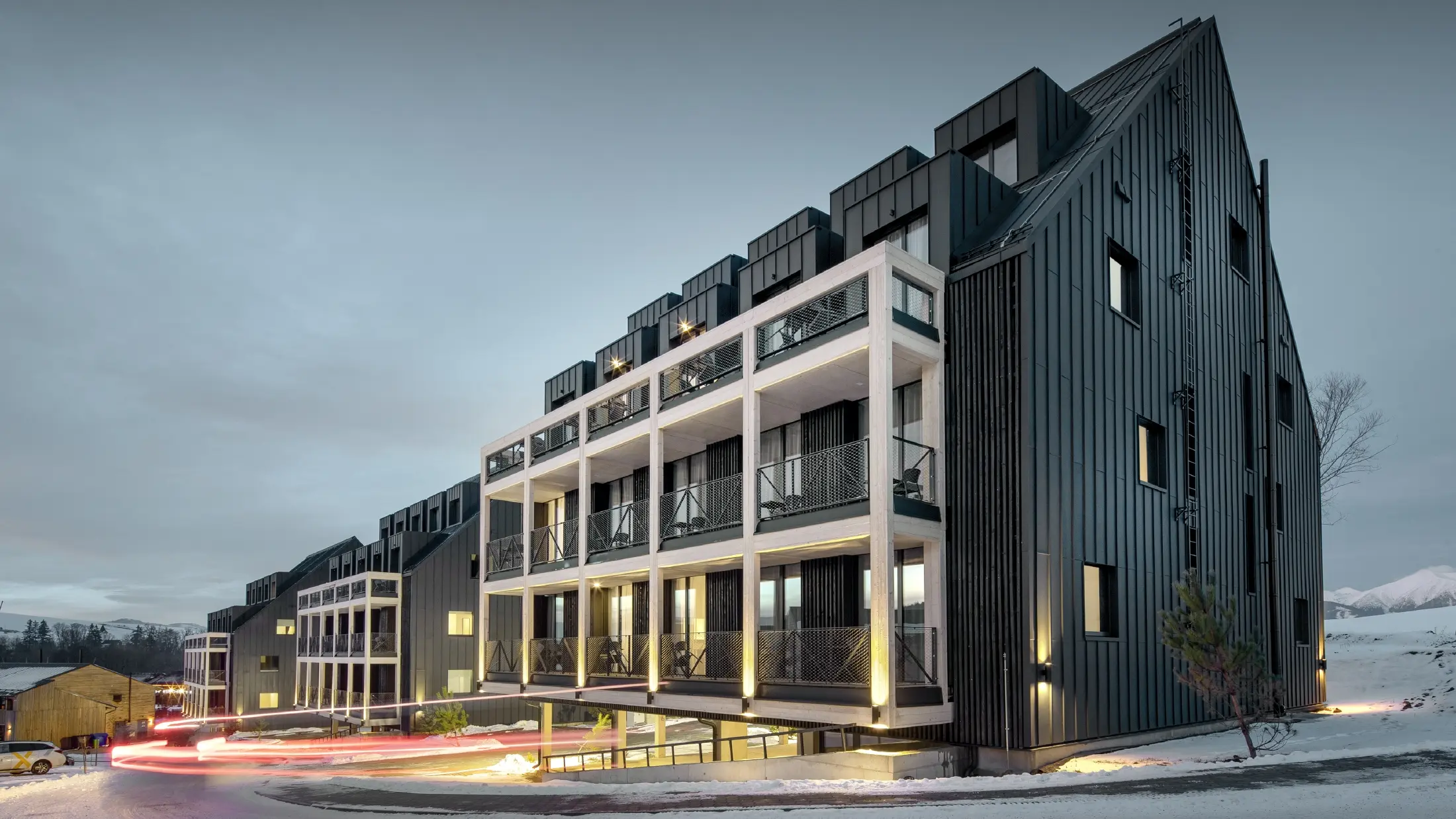 Ski resort in Slovakia with balconies and dormers, the façade is clad with PREFALZ standing seam in anthracite, just like the gable roof, snow-covered surroundings