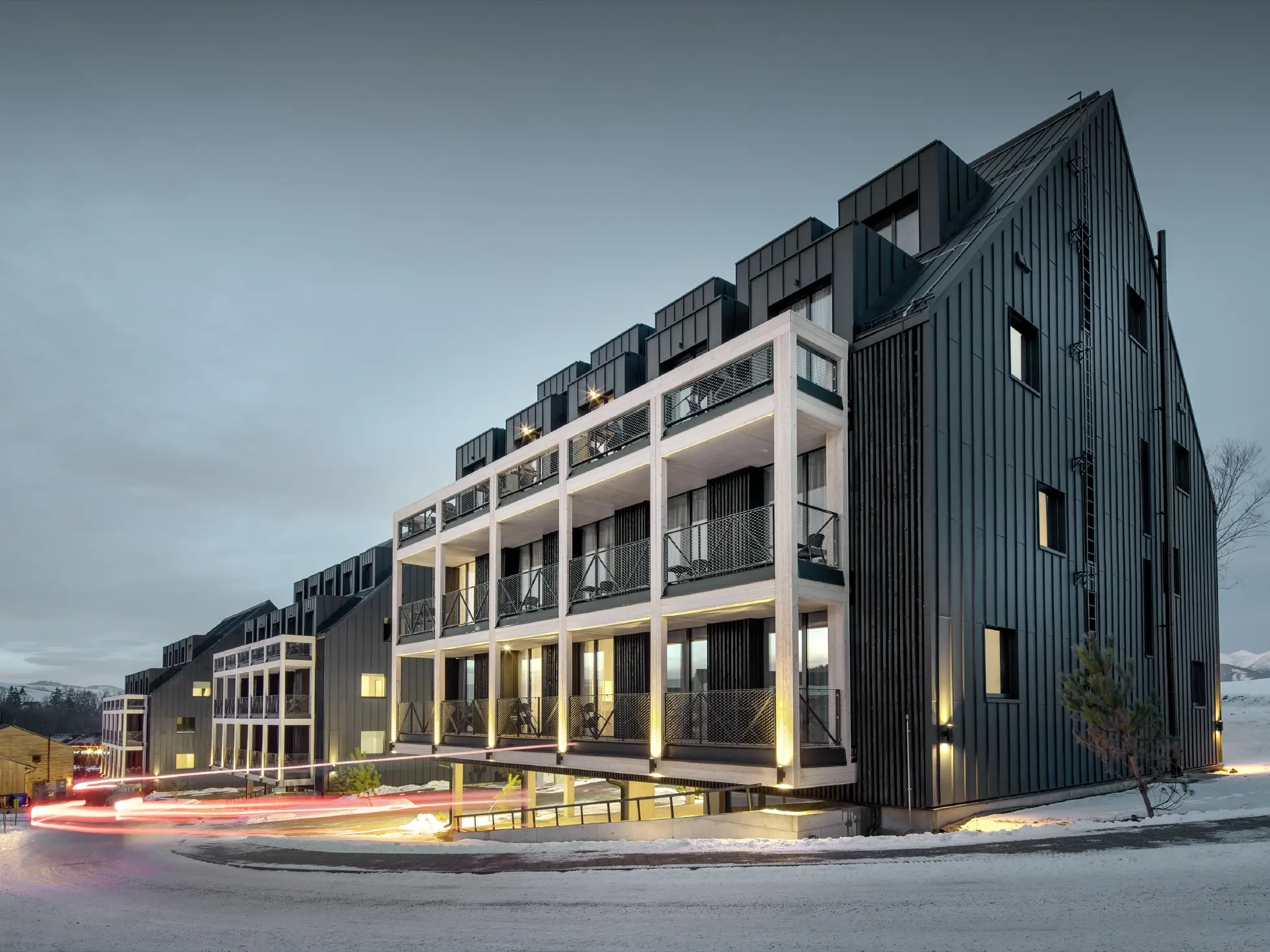 Ski resort in Slovakia with balconies and dormers, the façade is clad with PREFALZ standing seam in anthracite, just like the gable roof, snow-covered surroundings
