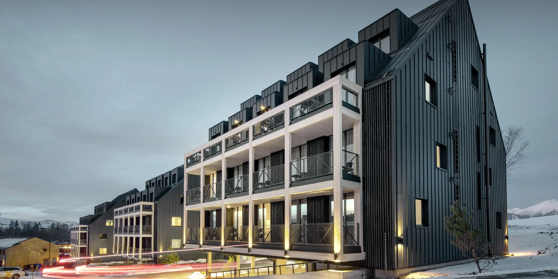 Ski resort in Slovakia with balconies and dormers, the façade is clad with PREFALZ standing seam in anthracite, just like the gable roof, snow-covered surroundings
