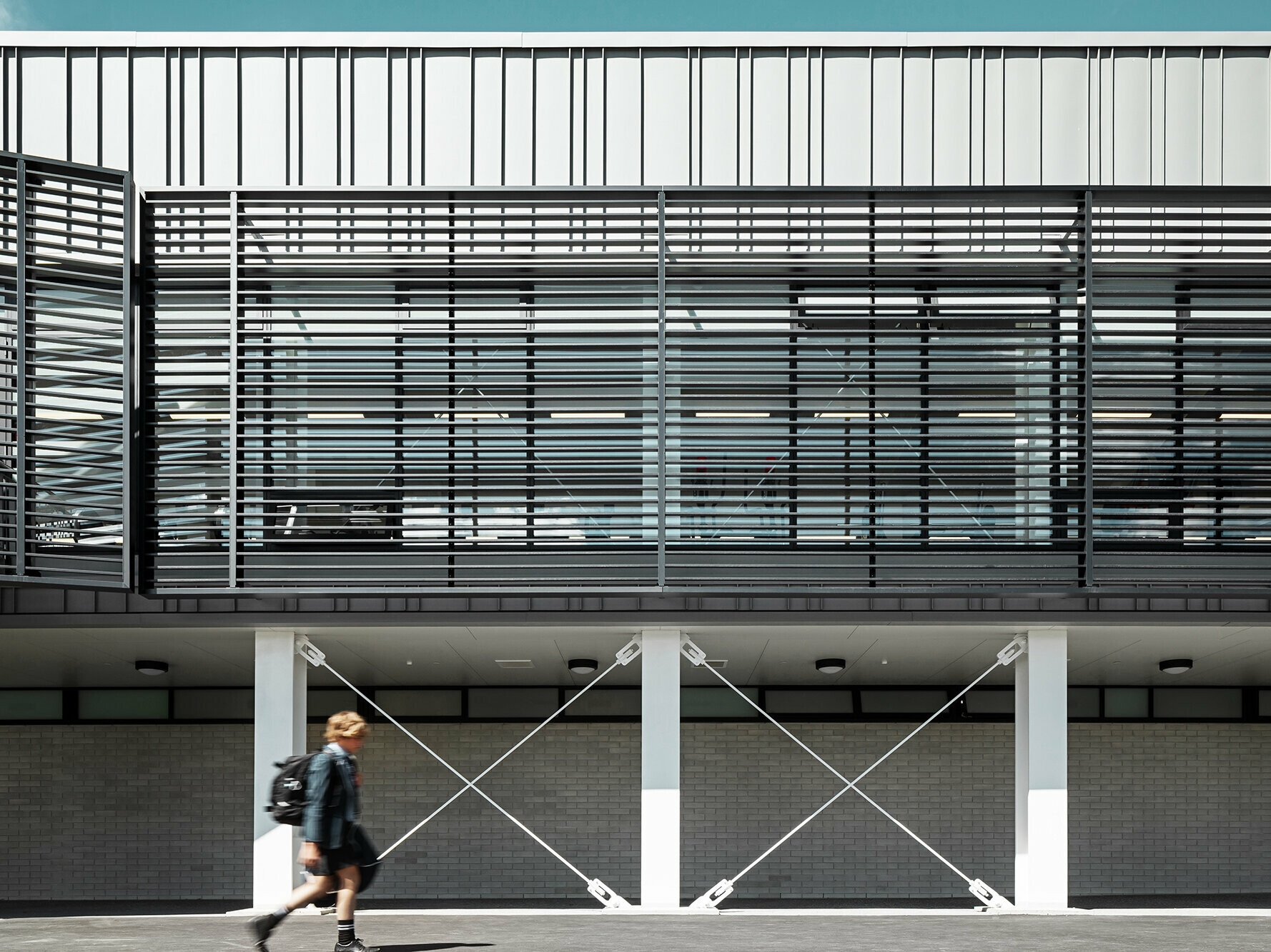 Frontal view of the protruding first floor, a student is walking past it.