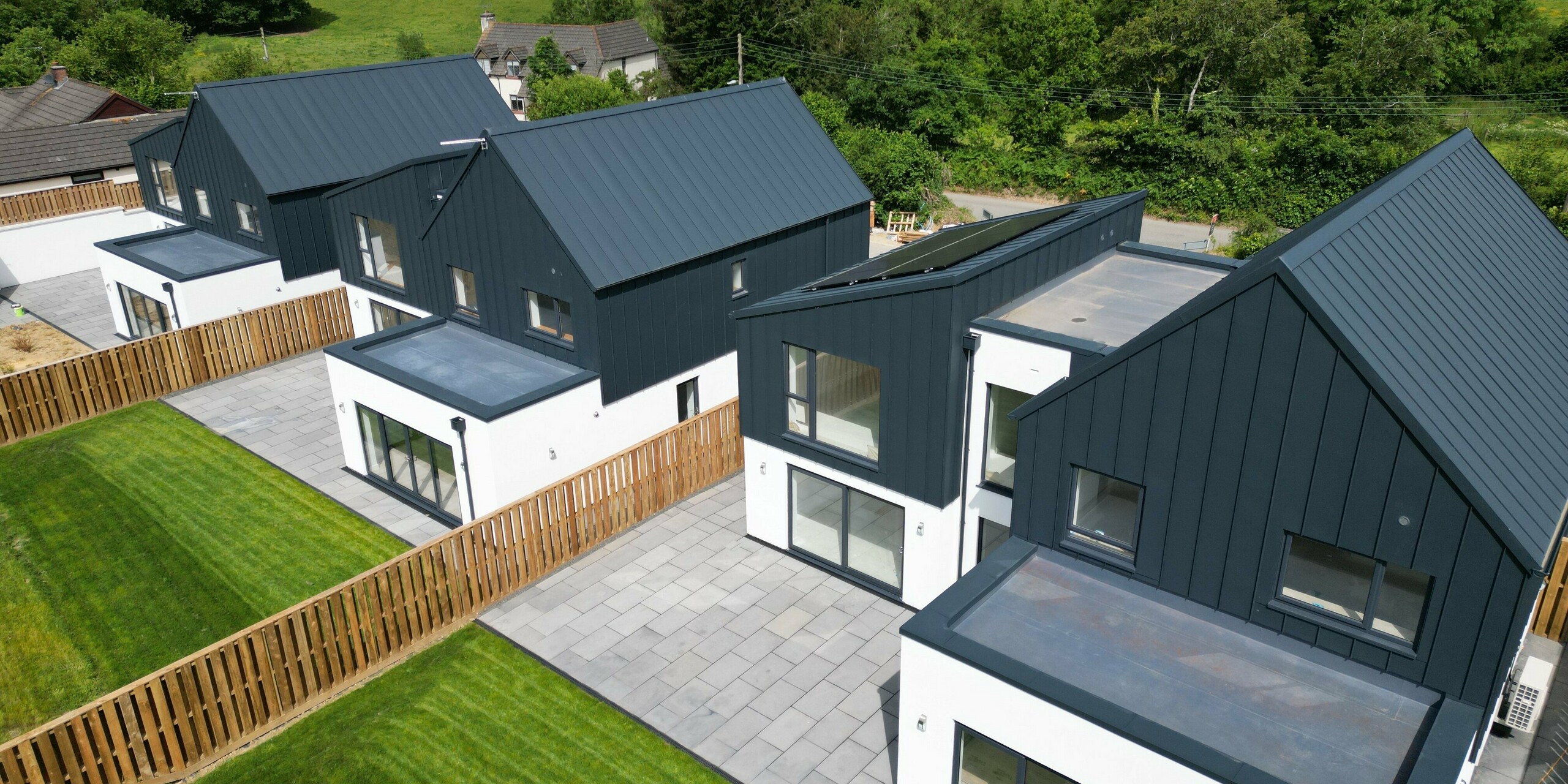 Side view of the detached houses in Bridgerule, Devon, with PREFALZ roof and façade in P.10 anthracite. The durable aluminium cladding emphasises the modern and weather-resistant character of the building – perfect for sustainable construction.