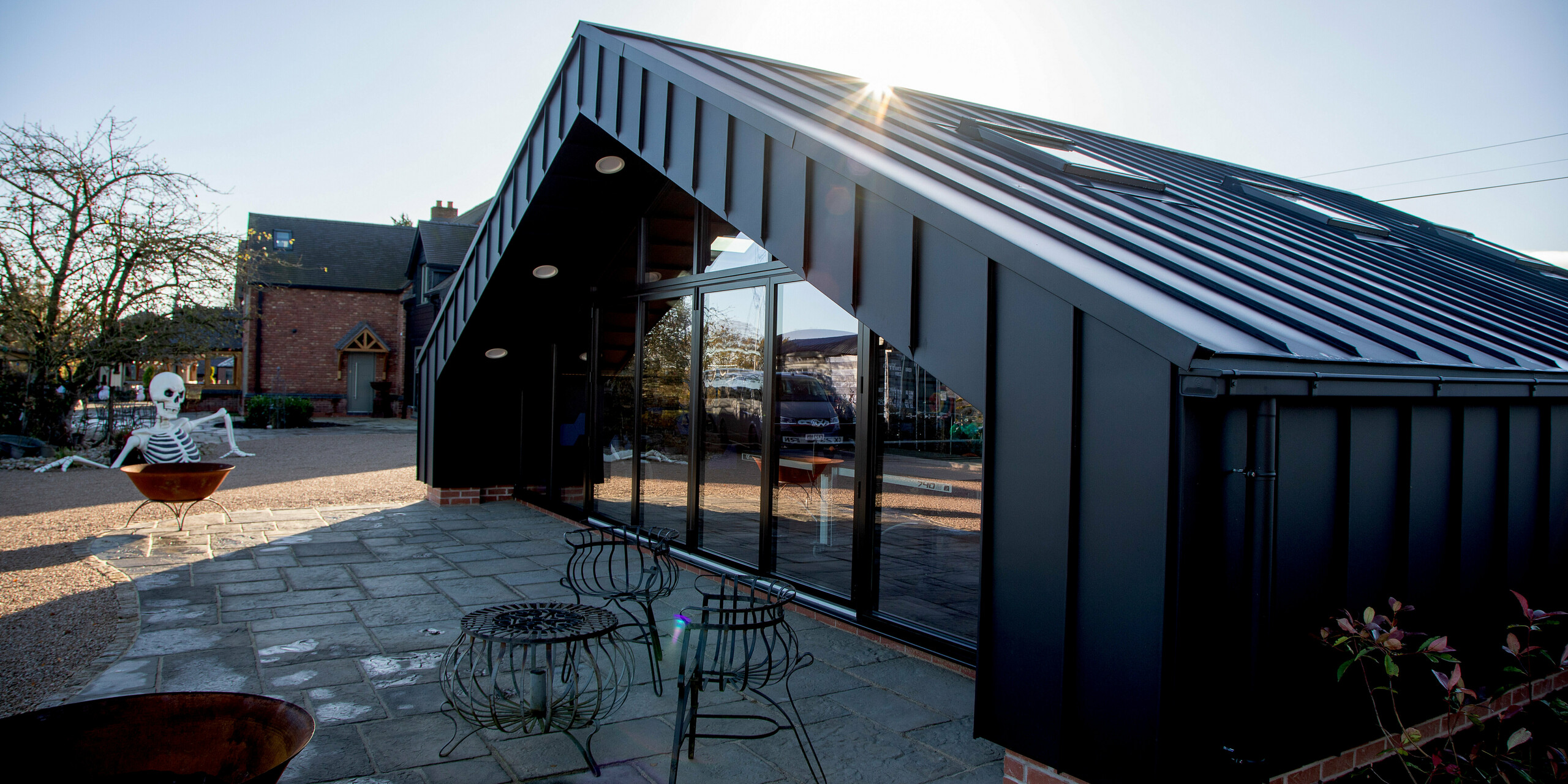 Exterior view of the modern leisure building clad entirely with PREFA aluminum and PREFALZ in P.10 black. The sharp standing seam lines, expansive glass façade and striking roof geometry create a dynamic architectural look. The durable, weather‑resistant aluminum surface ensures long‑lasting performance and enhances the building’s bold presence in the outdoor setting.