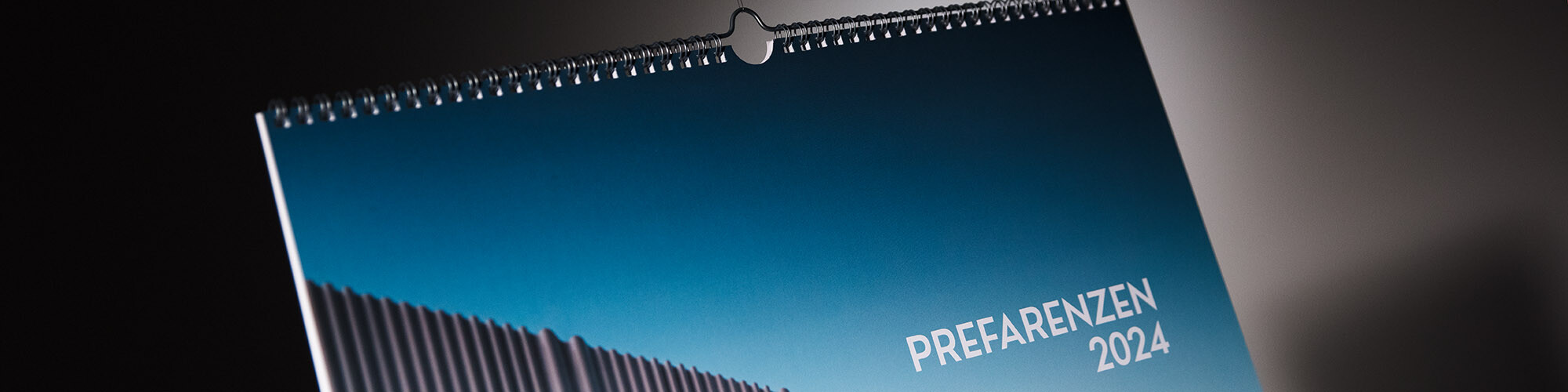 A section of the title page of the calendar up close; part of a wavy aluminium façade as well as "PREFARENZEN 2024" can be seen.