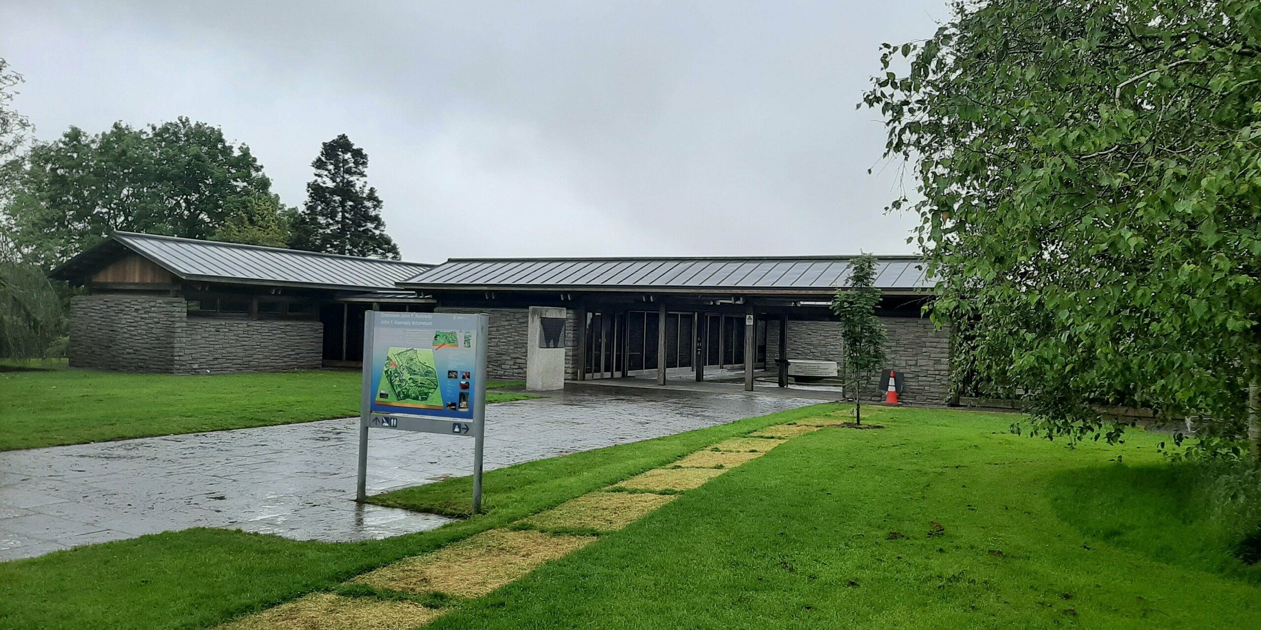 Picture of the new roof of the visitor center with PREFALZ in the colour P.10 dark grey. Around the vistor center you can see a sign and a tree.