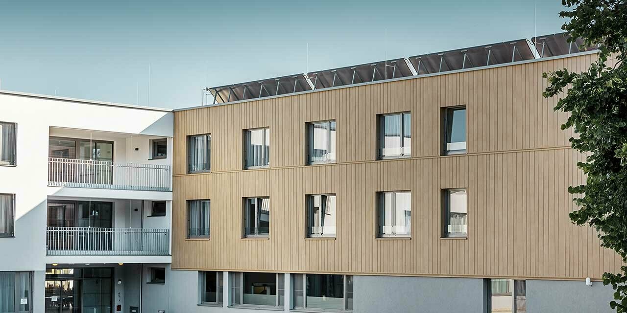 Retirement home with a flat roof and a sand brown siding façade made by PREFA