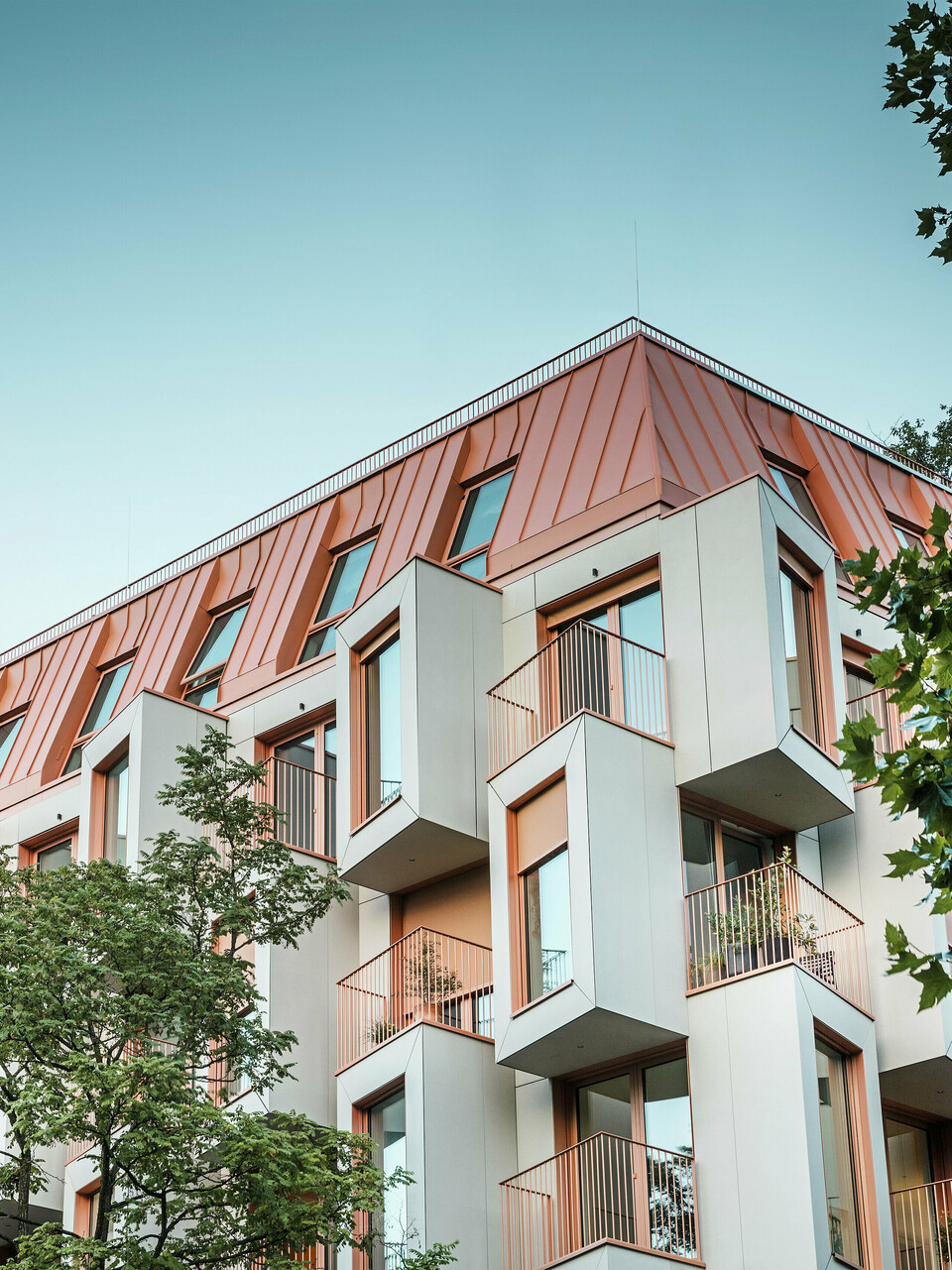 Modern residential architecture in the Van B project in Munich with an innovative bay window façade and striking PREFALZ aluminium roof in the special colour IGP Orange HDP from PREFA. The high-quality roofing material impresses with its extreme durability, high resistance and colour fastness. In combination with the cubic façade design and large window areas, the result is a harmonious overall appearance that combines functionality, design and sustainability at the highest level – ideal for urban living.