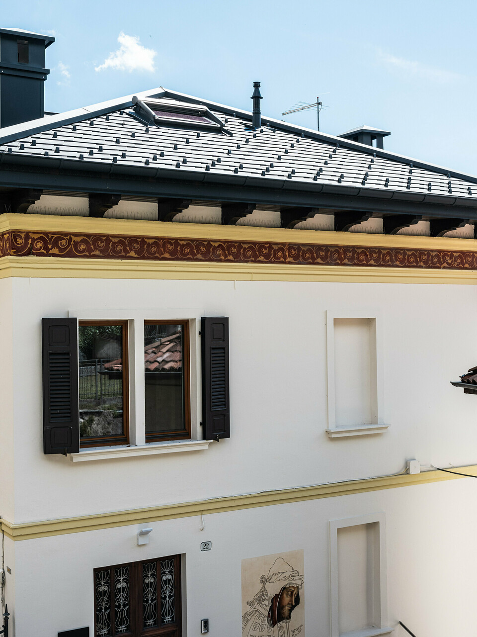 Restauriertes Gebäude in Belluno, gekennzeichnet durch ein PREFA Dach mit anthrazitfarbenen Aluminiumschindeln, die die strukturelle Integrität wahren. Die klassische Fassade mit dekorativen Frieselementen fügt sich nahtlos in die malerische italienische Landschaft ein und wird durch das moderne, langlebige und stilvolle PREFA Dachsystem in der Farbe P.10 Anthrazit abgerundet.