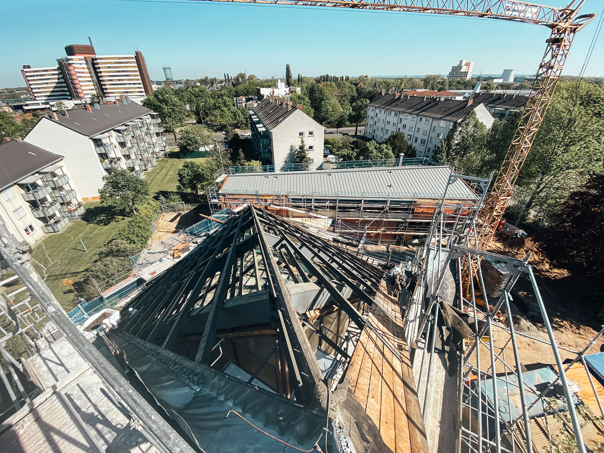 In this picture, the raw construction of the church can be seen by daylight. In the background there are residential buildings.