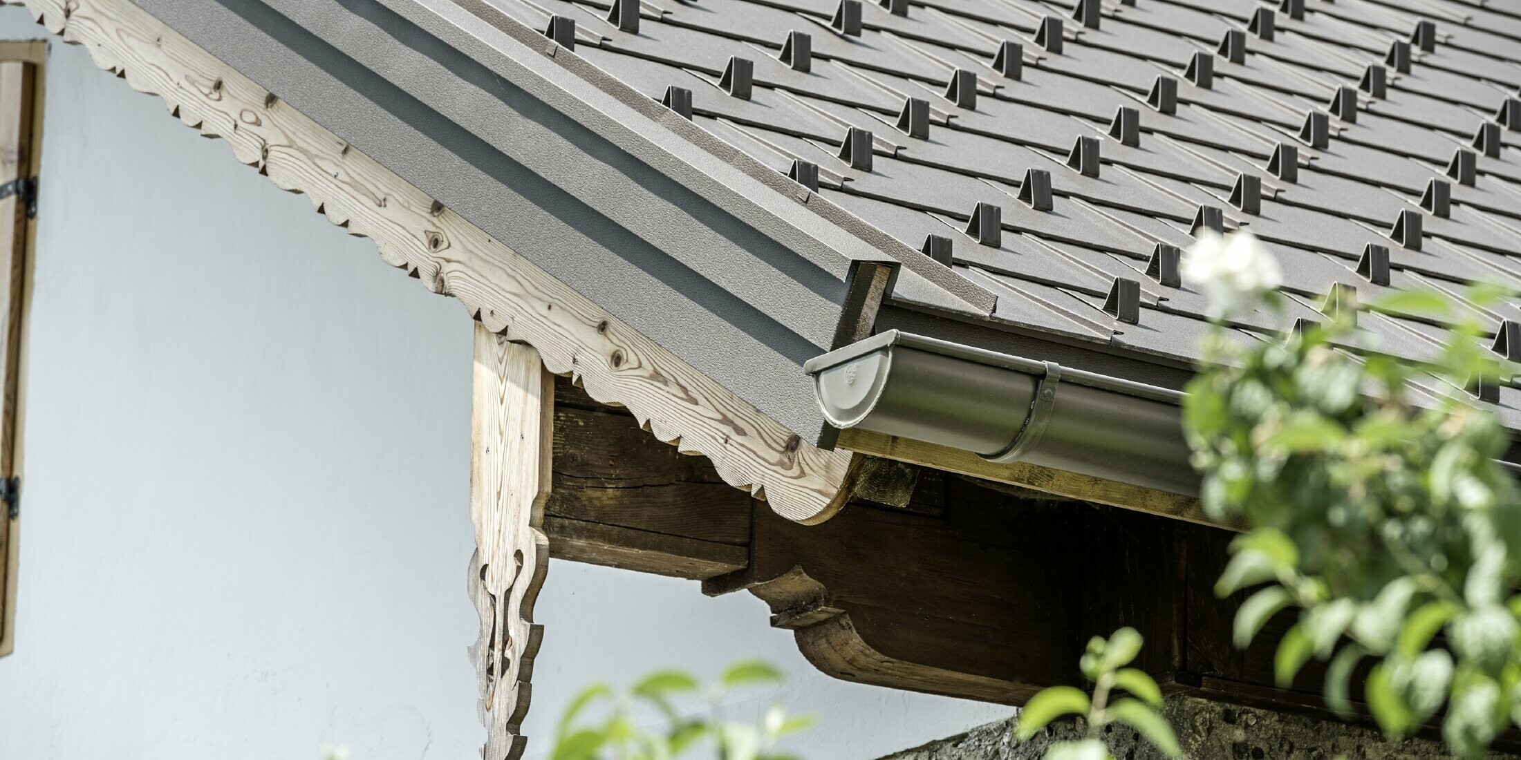 PREFA gutter in brown with the PREFA R.16 roof tile and verge trim, also in brown