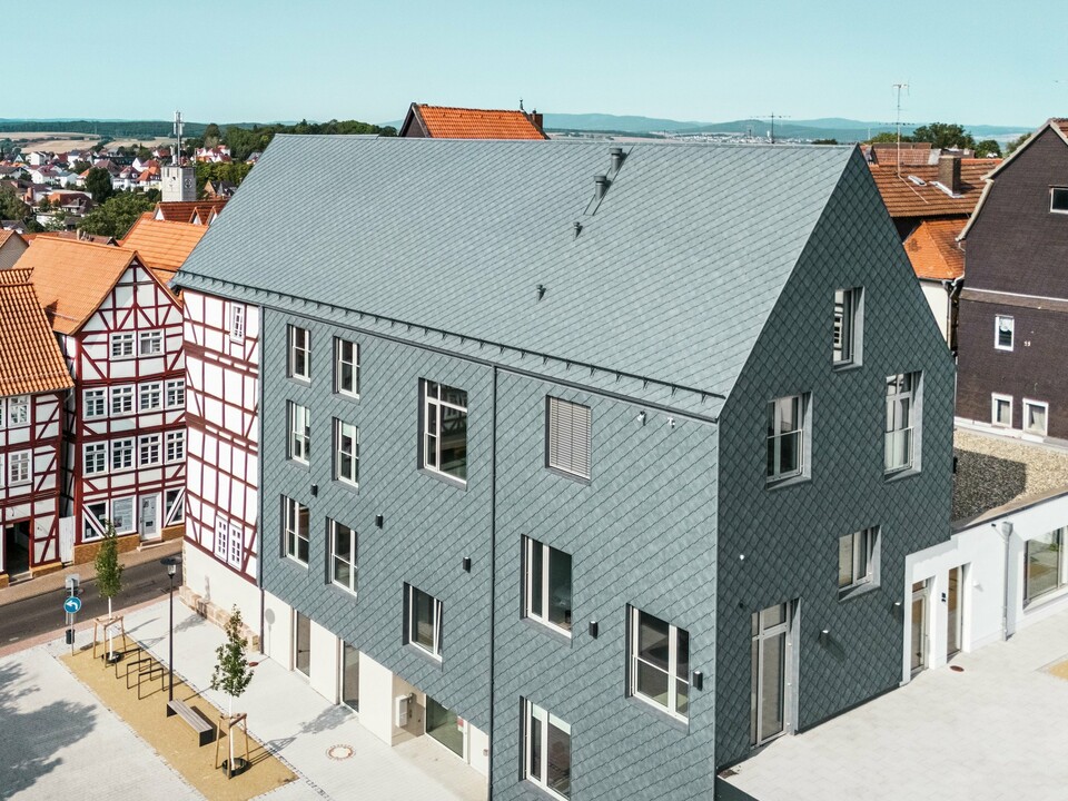 Hochwertige Sanierung des Volkshauses in Homberg, DE, eingebettet in die historische Altstadt mit Fachwerkhäusern. Dach, Giebel und große Teile der Fassade sind mit robusten und eleganten PREFA Aluminium-Rauten 29 × 29 in P.10 Steingrau eingedeckt. Die schuppenartige Aluminiumdeckung ist langlebig, farbbeständig und fügt sich perfekt in die geschichtsträchtige Umgebung ein.