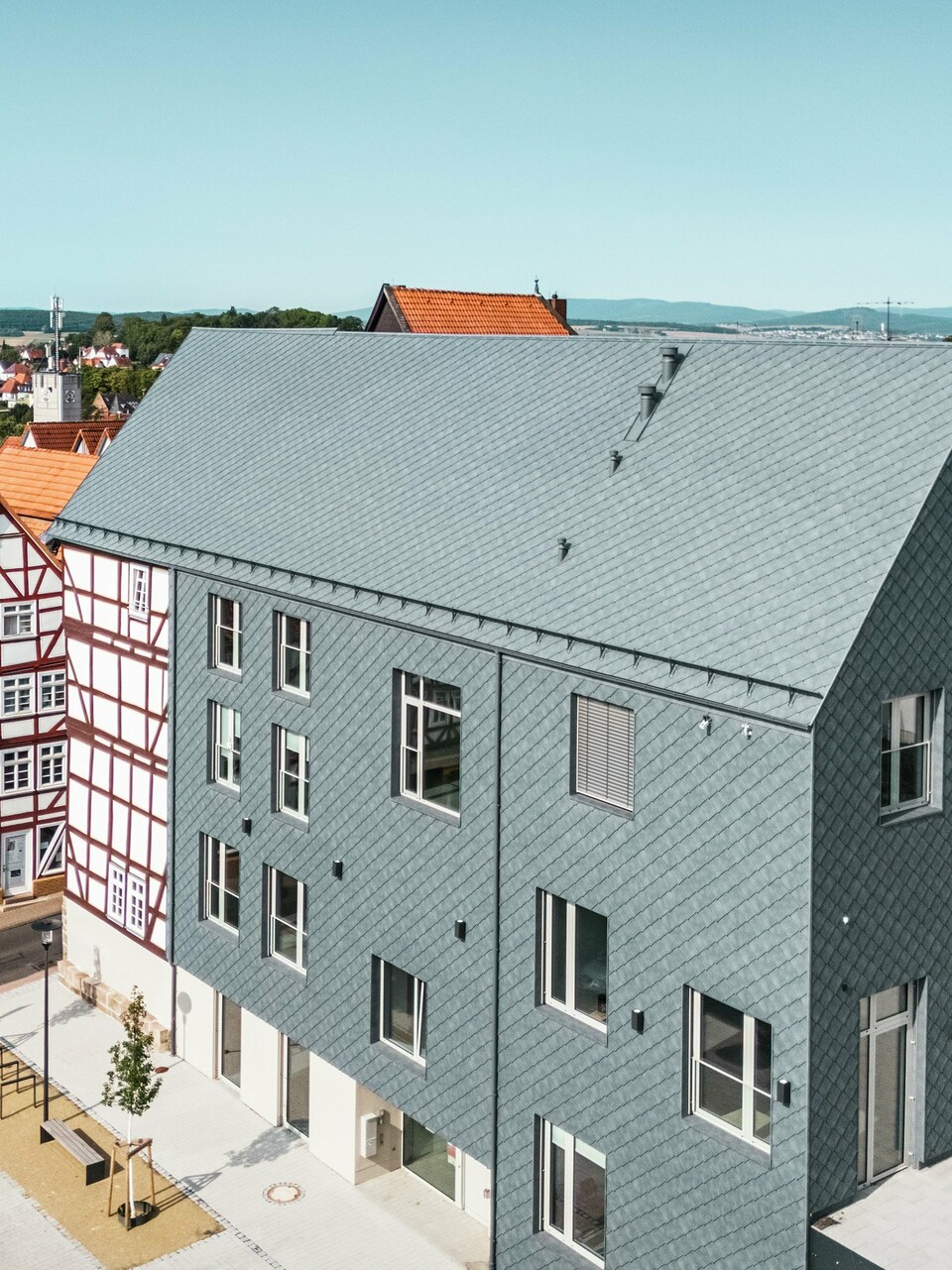 Hochwertige Sanierung des Volkshauses in Homberg, DE, eingebettet in die historische Altstadt mit Fachwerkhäusern. Dach, Giebel und große Teile der Fassade sind mit robusten und eleganten PREFA Aluminium-Rauten 29 × 29 in P.10 Steingrau eingedeckt. Die schuppenartige Aluminiumdeckung ist langlebig, farbbeständig und fügt sich perfekt in die geschichtsträchtige Umgebung ein.